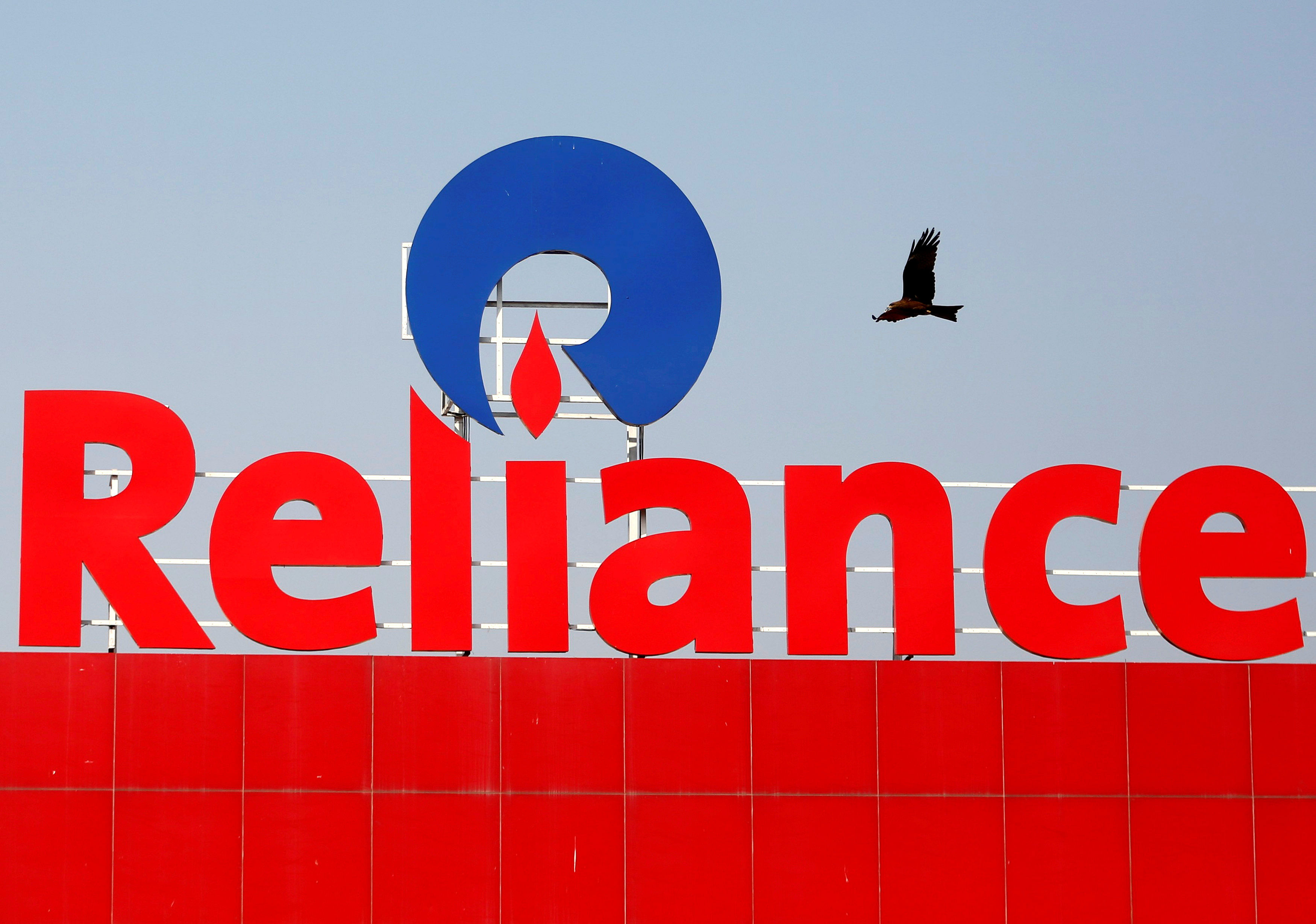  A bird flies past a Reliance Industries logo. Credit: Reuters