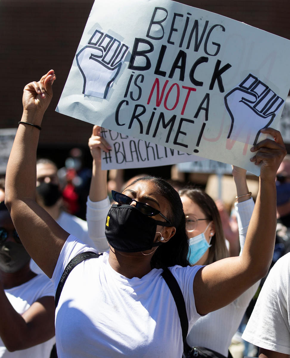 People hold signs during a protest against racial inequality and police brutality (Reuters Photo)