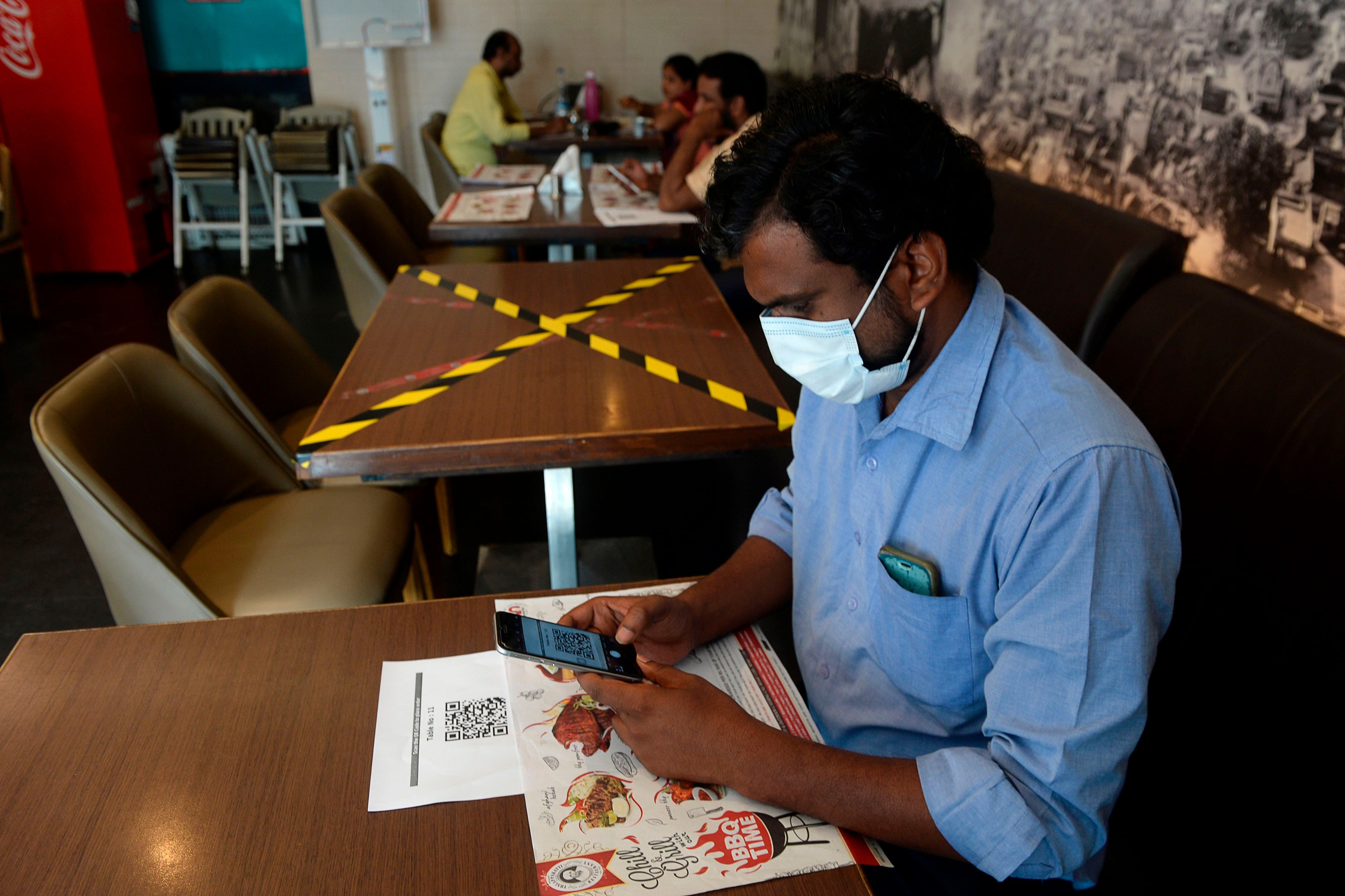 A customer scans a QR code on his mobile phone to access to a menu at a restaurant after the government eased a nationwide lockdown imposed as a preventive measure against the COVID-19 coronavirus, in Chennai on June 8, 2020. (AFP Photo)