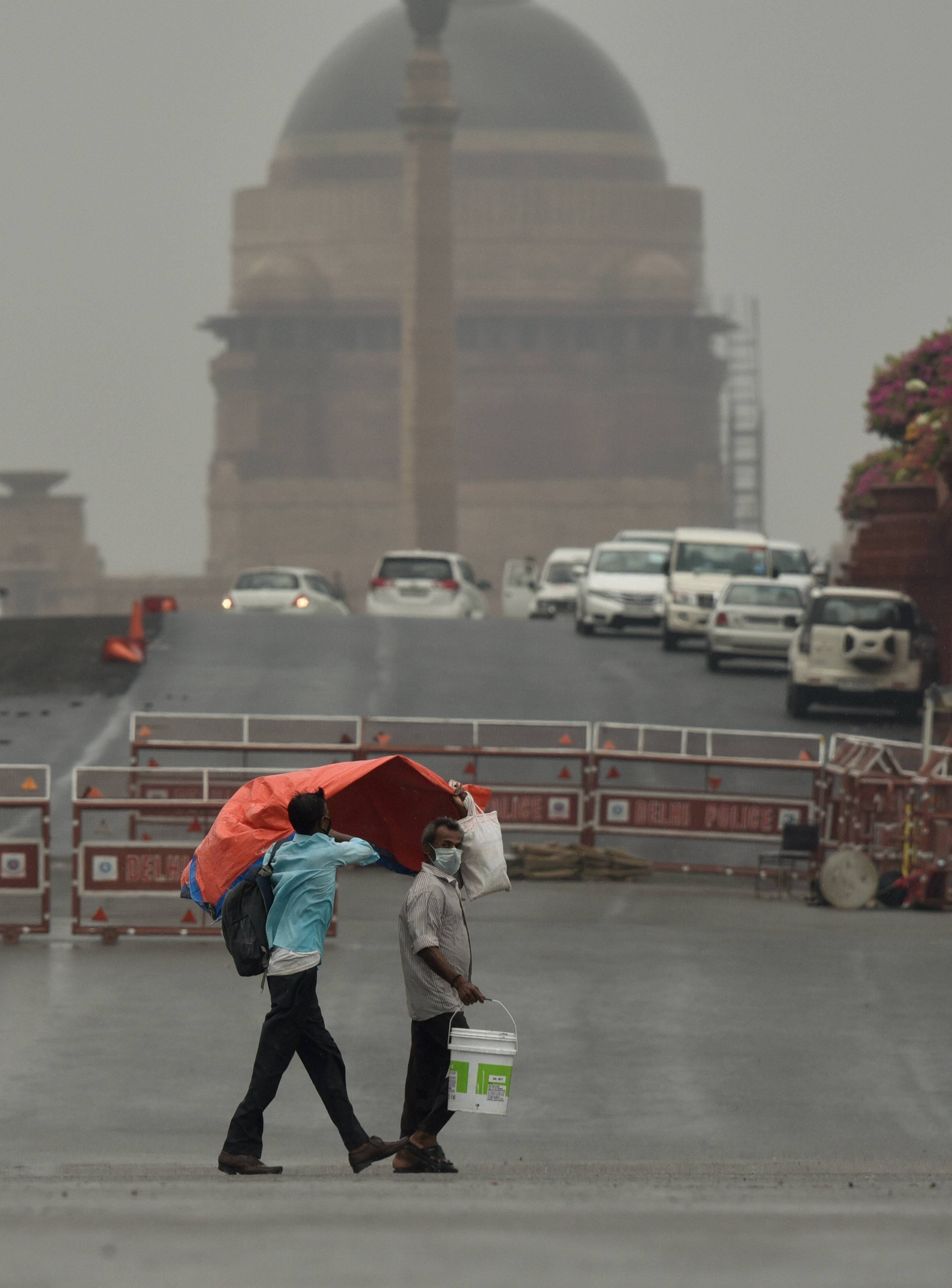 Commuters walk in rain at Vijay Chowk during the ongoing COVID-19 lockdown, in New Delhi, Wednesday, June 10, 2020. (PTI Photo)