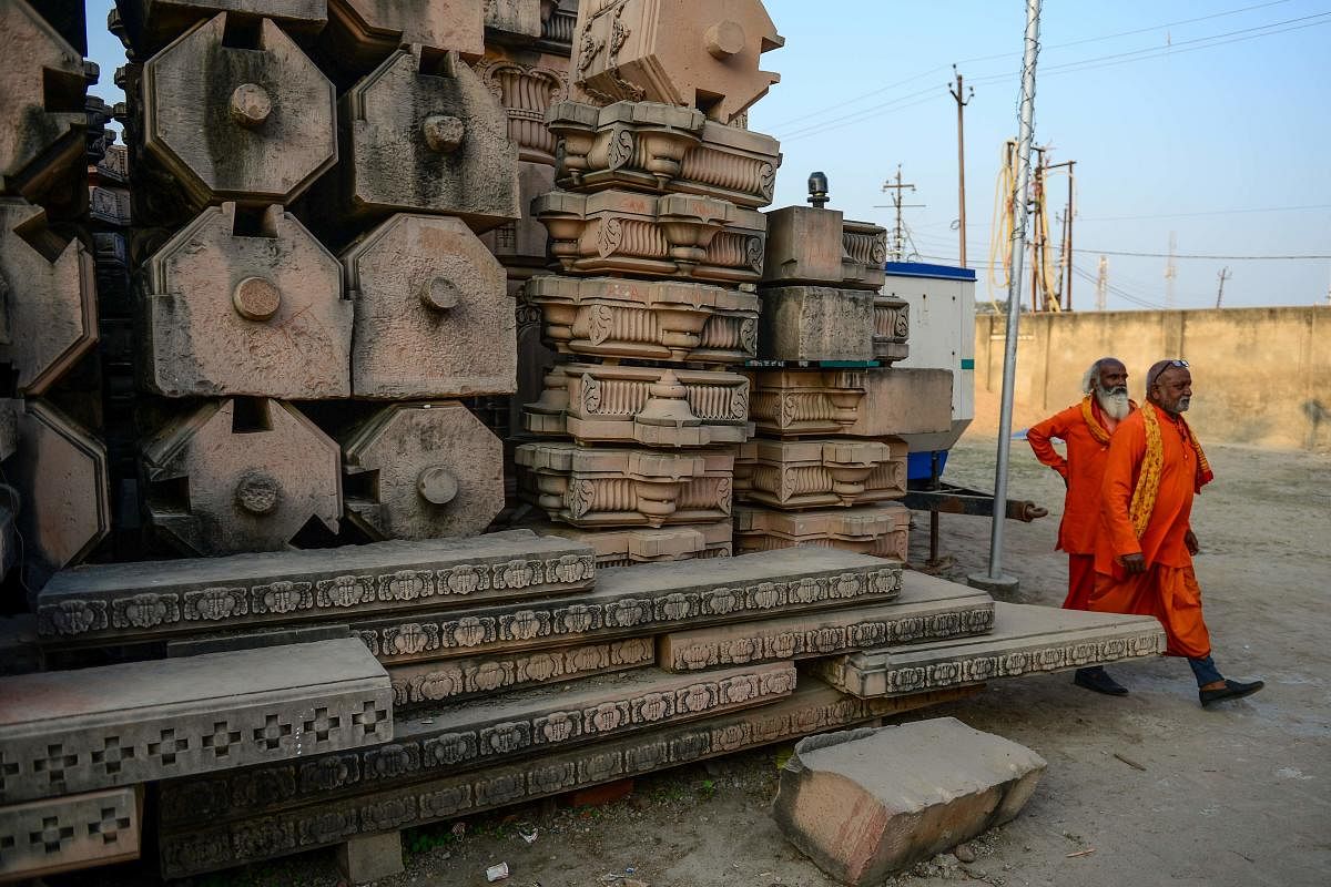 In this picture taken on November 12, 2019, Hindu devotees walk past stone slabs earmarked for the construction of a Hindu God Ram temple Ram Janmabhoomi Nyas workshop in Ayodhya, after the Supreme Court verdict on the disputed religious site. (AFP)