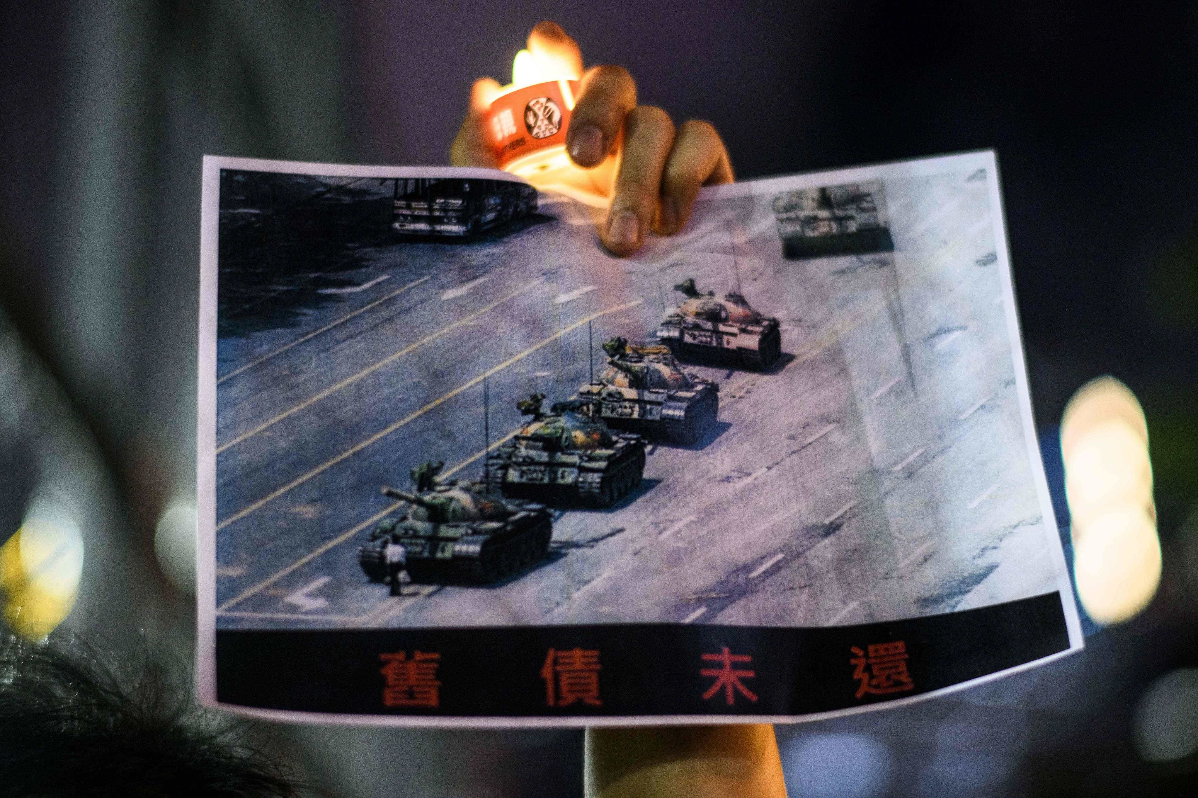 A man holds a poster of the famous 'Tank Man' standing in front of Chinese military tanks at Tiananmen Square in Beijing on June 5, 1989, during a candlelit remembrance in Victoria Park in Hong Kong. Credit: AFP