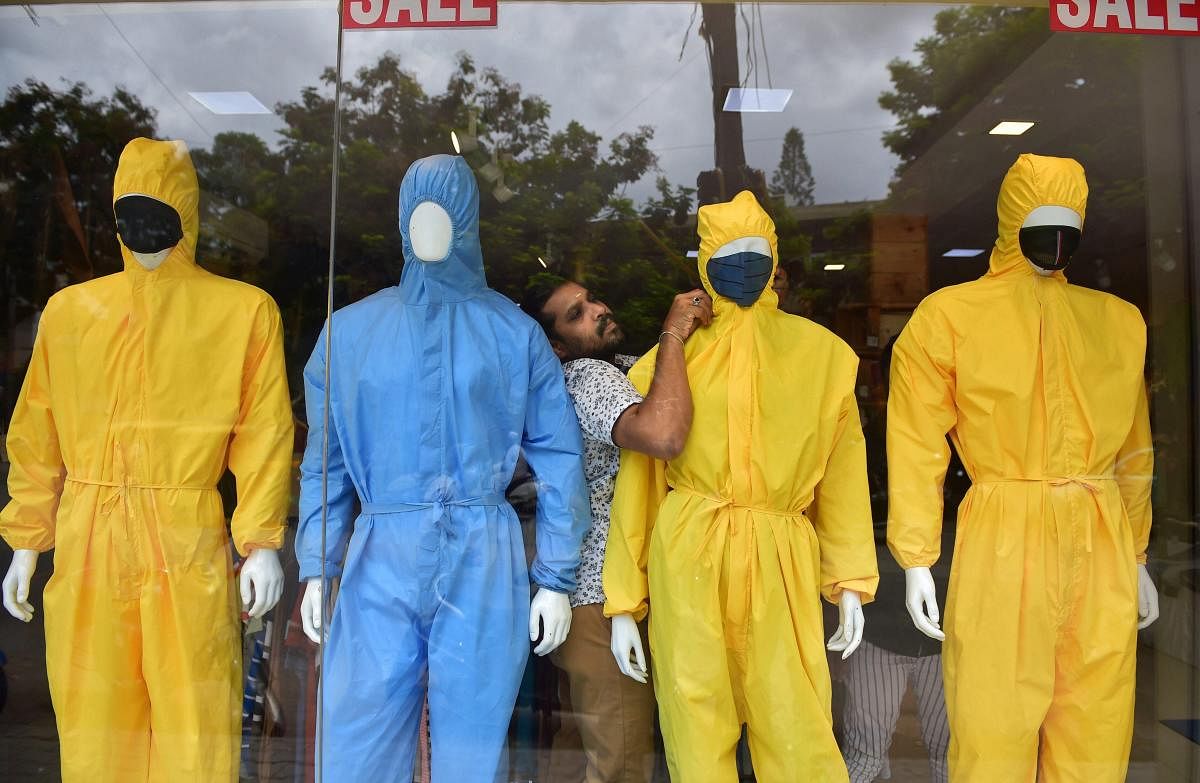 A salesman arranges raincoats and PPE suits on mannequins at a store after the authorities permitted opening of apparel stores in Bengaluru, Wednesday, June 10, 2020. PTI