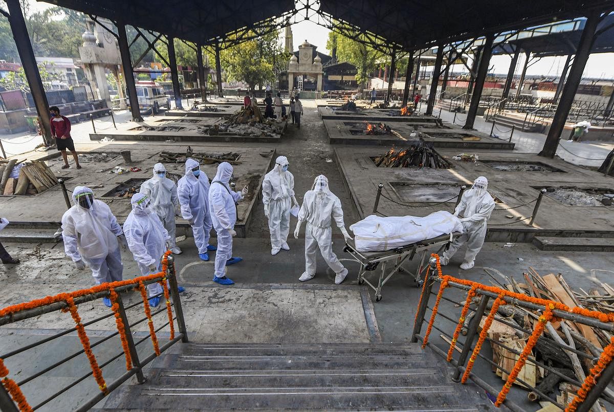 Health workers and family members wearing protective suits perform the last rites of a person who died of COVID-19 (PTI Photo)
