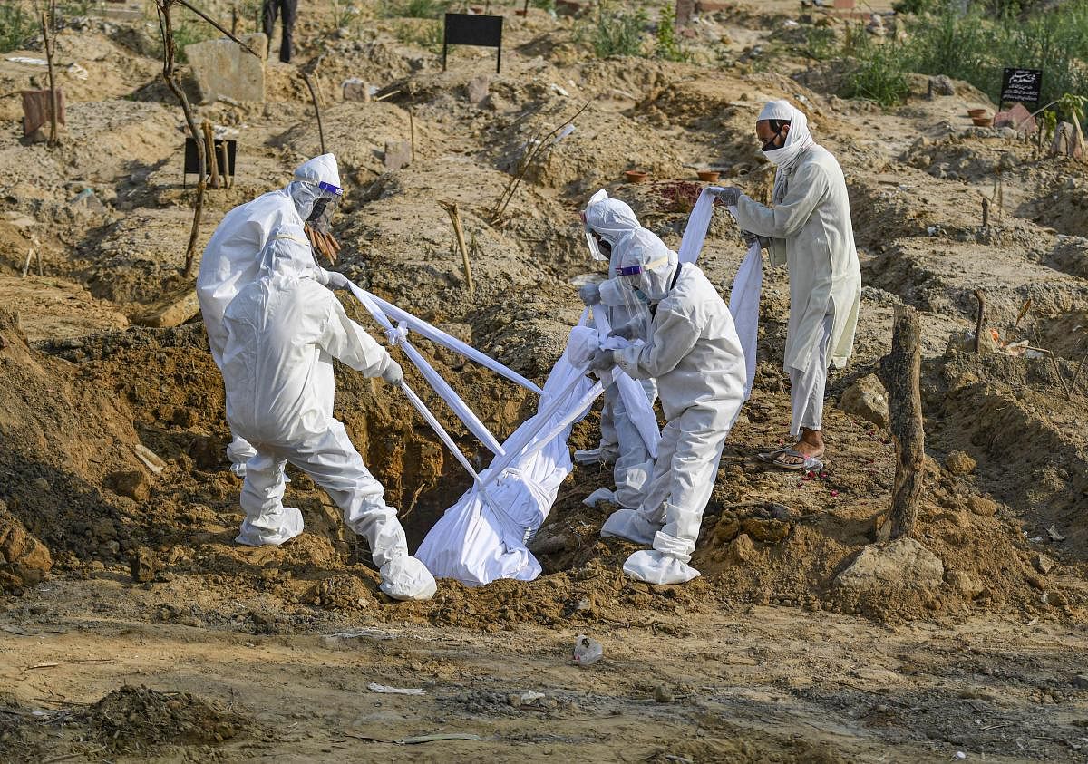 Relatives wearing protective suits bury the body of a man who died due to coronavirus infection during his funeral at a graveyard, amid the ongoing COVID-19 lockdown, in New Delhi, Friday, June 12, 2020. Credit/PTI Photo