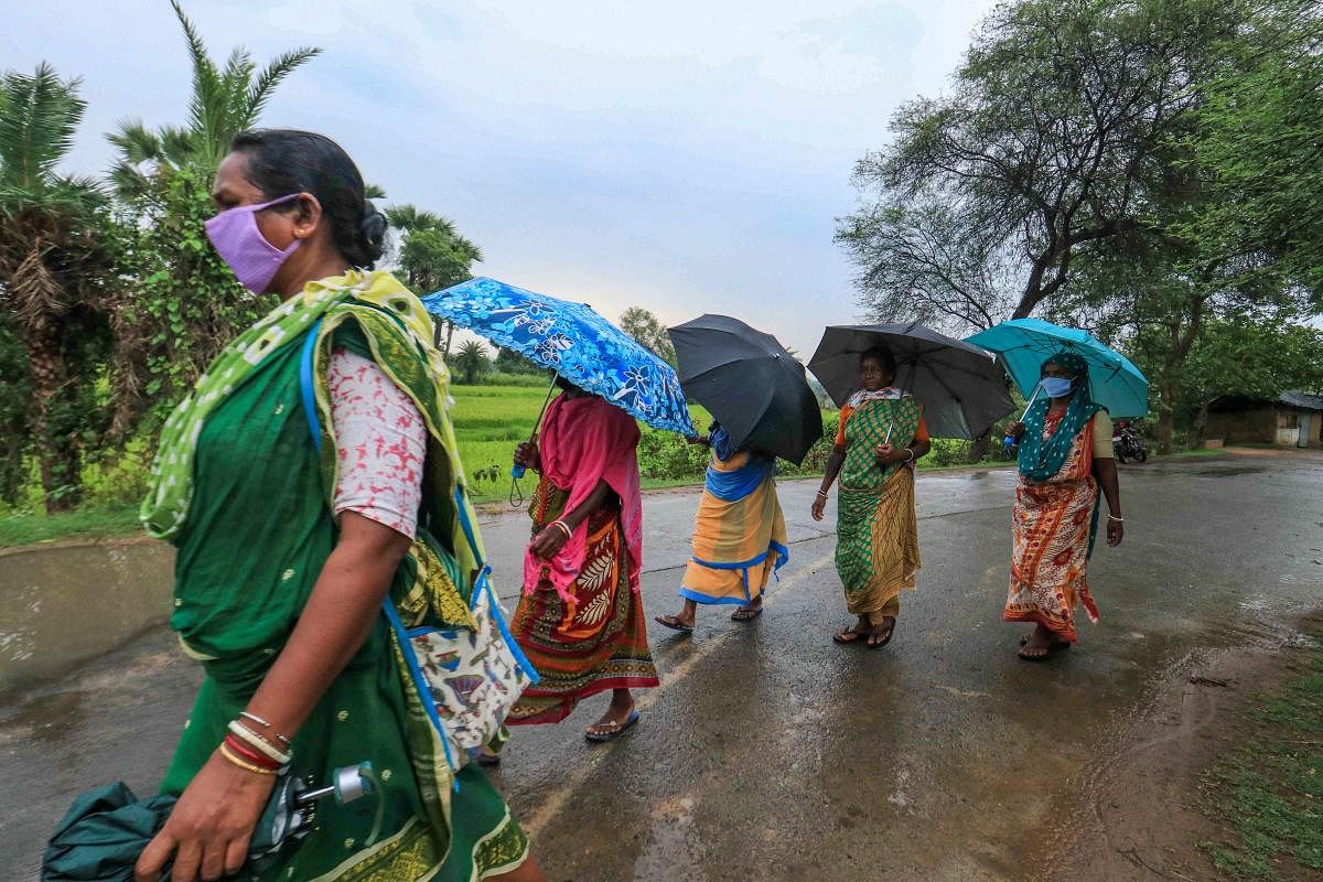Women hold umbrellas as they walk on a deserted road during Monsoon rain, amid the ongoing COVID-19 nationwide lockdown, in Birbhum district. PTI