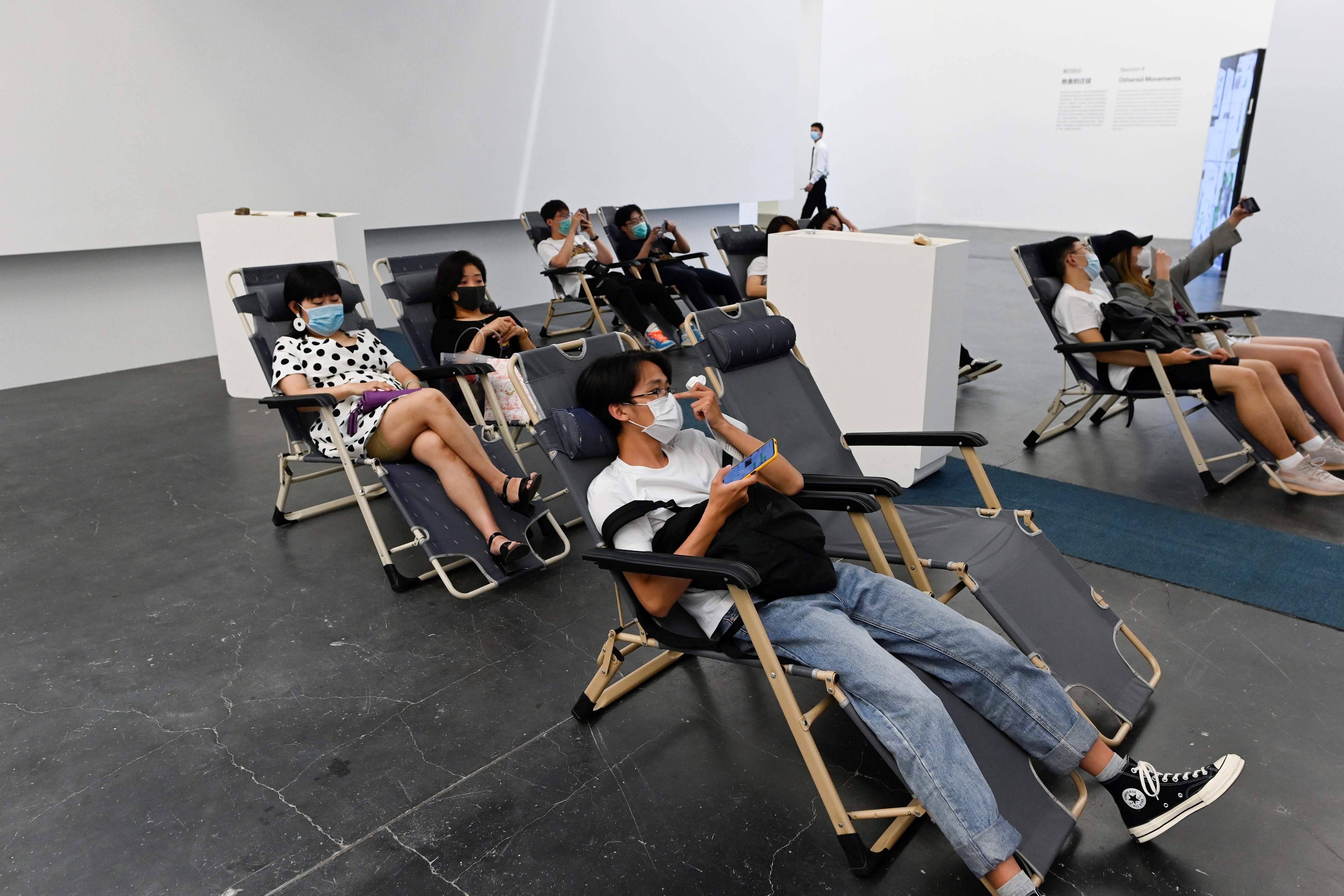 Visitors wearing face masks amid concerns of the COVID-19 coronavirus rest on chairs at the exhibition 'Meditations in an Emergency' at UCCA Center for Contemporary Art in Beijing. Credits: AFP Photo