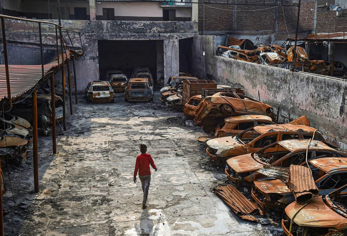  A man walks past the charred remains of vehicles set ablaze by rioters at parking during the anti-CAA protests in February, at Shiv Vihar area of Northeast Delhi, Wednesday, June 3, 2020. Credit/PTI Photo