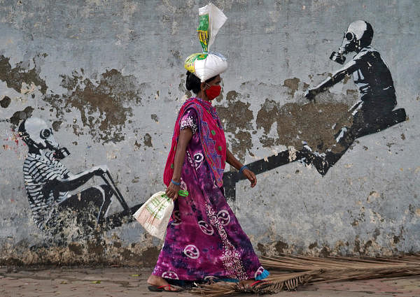 A woman wearing a protective face mask walks past a graffiti, after authorities eased lockdown restrictions that were imposed to slow the spread of the coronavirus disease (COVID-19), in Mumbai, India, June 12, 2020. Credit: Reuters Photo