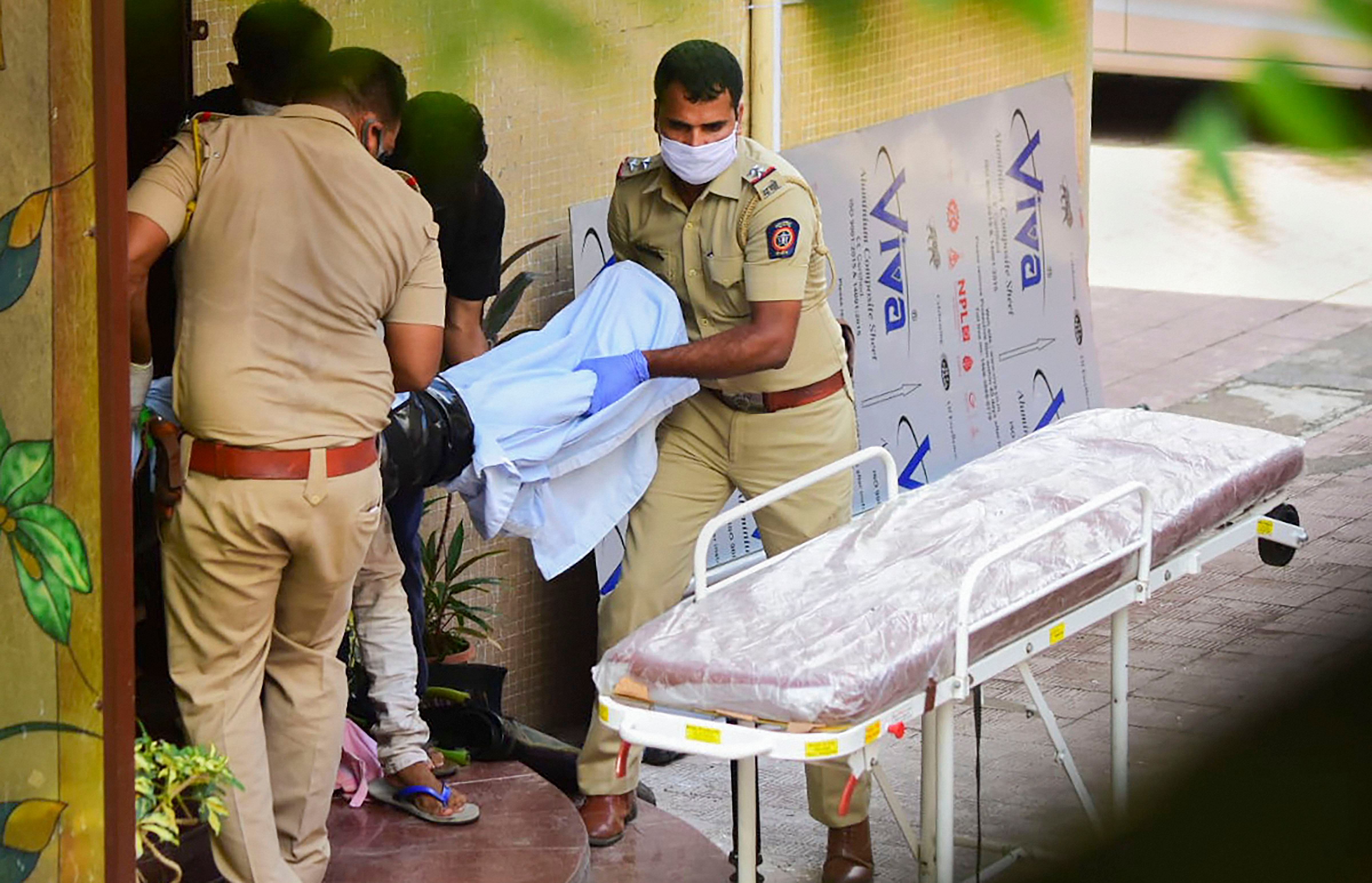Police personnel take the body of Bollywood actor Sushant Singh Rajput towards an ambulance after he was found hanging at his apartment, in Mumbai. Credits: PTI Photo