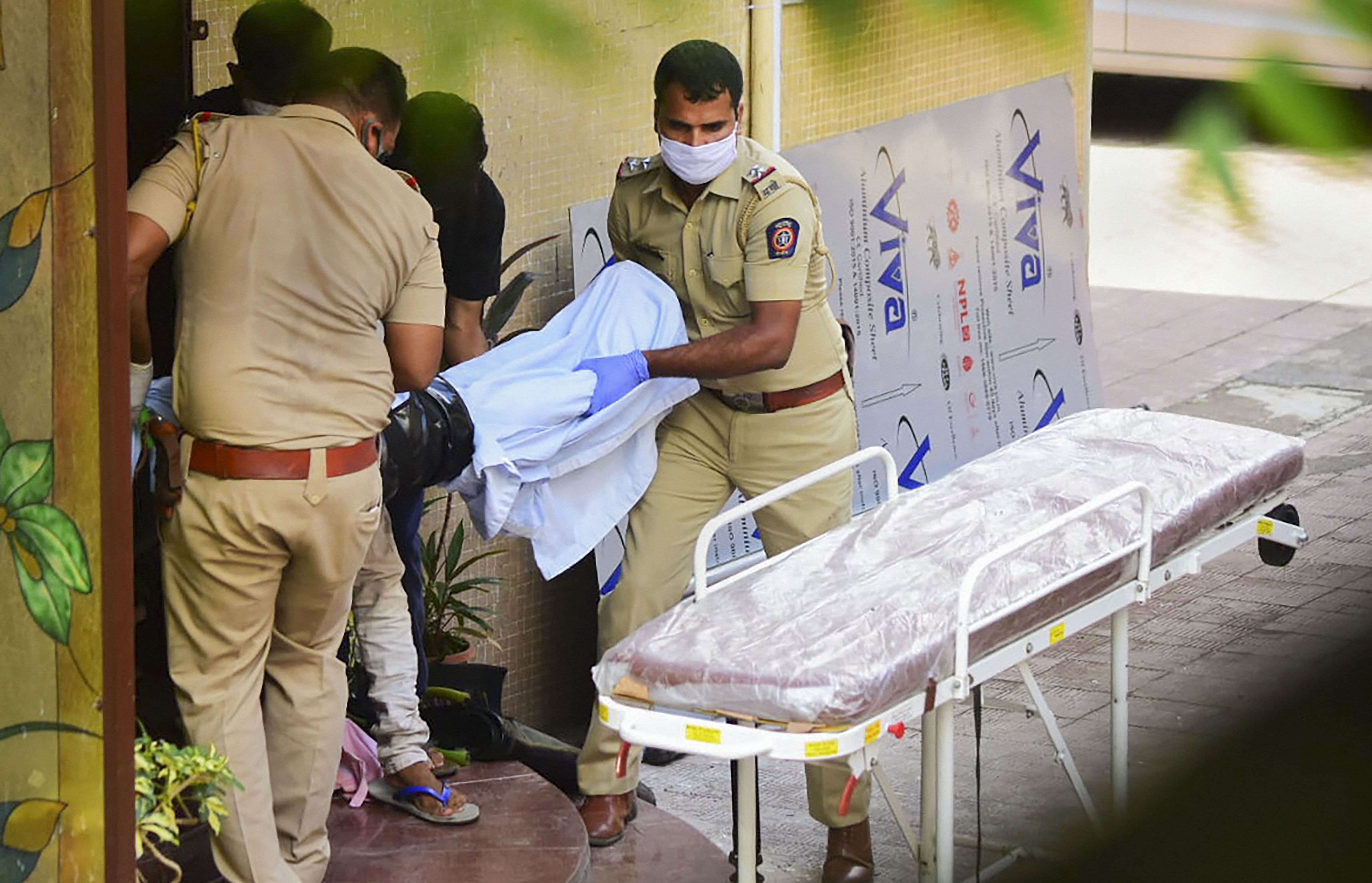 Police personnel take the body of Bollywood actor Sushant Singh Rajput towards an ambulance after he was found hanging at his apartment, in Mumbai. Credits: PTI Photo