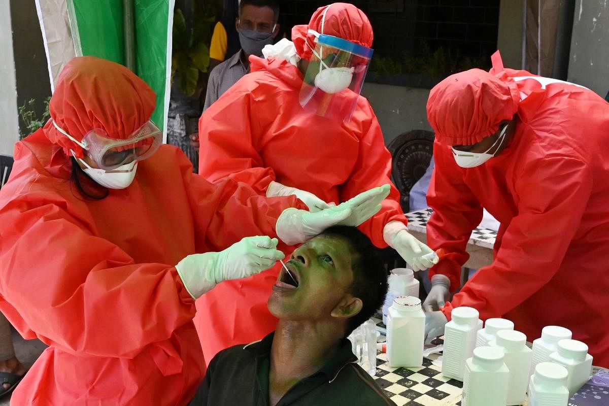 A medical worker (L) wearing Personal Protective Equipment (PPE) uses a swab to collect a sample from a man for a COVID-19 (AFP Photo)