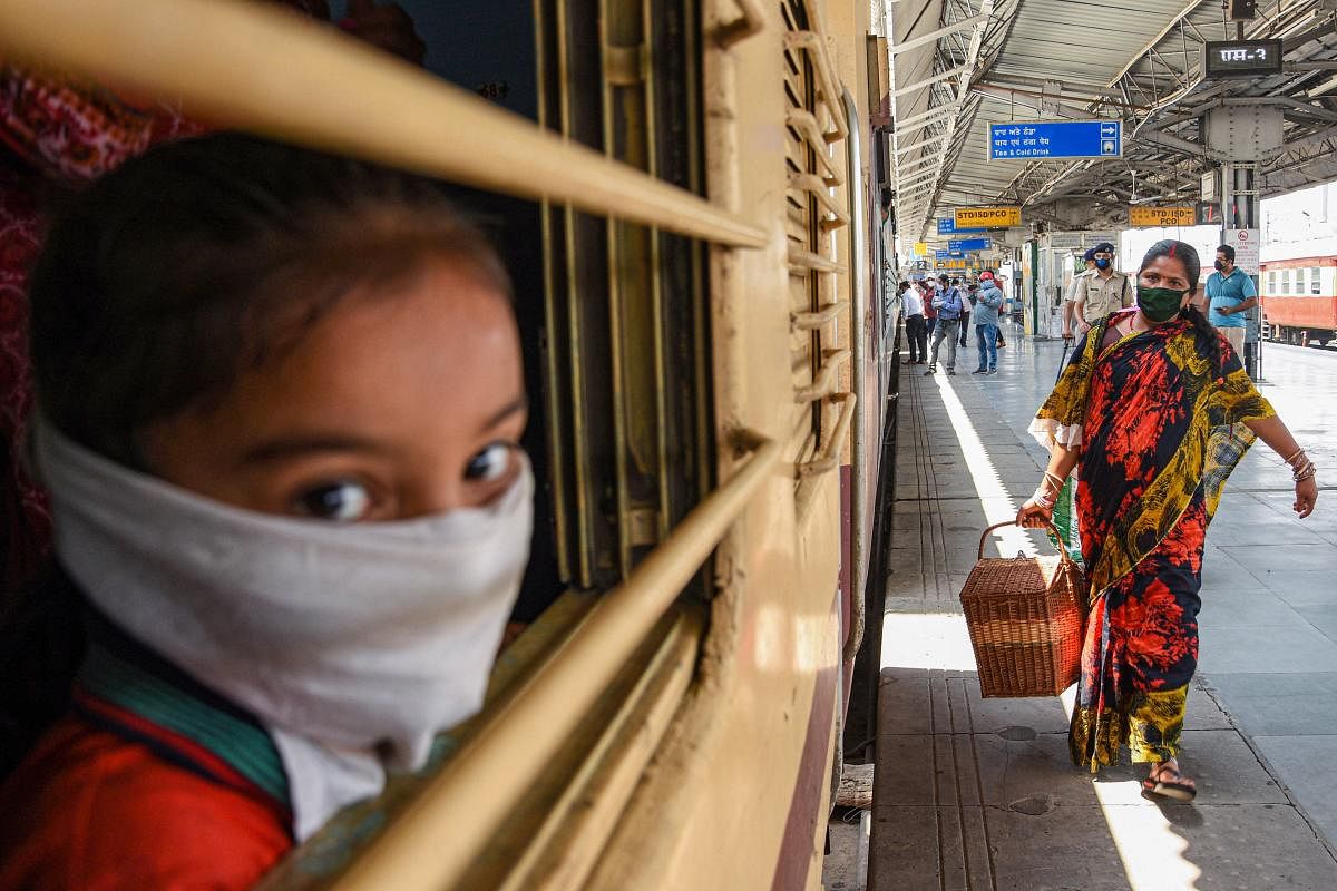 A girl, wearing a mask, looks through the window after boarding a train at a railway station, during the ongoing COVID-19 lockdown (PTI Photo)