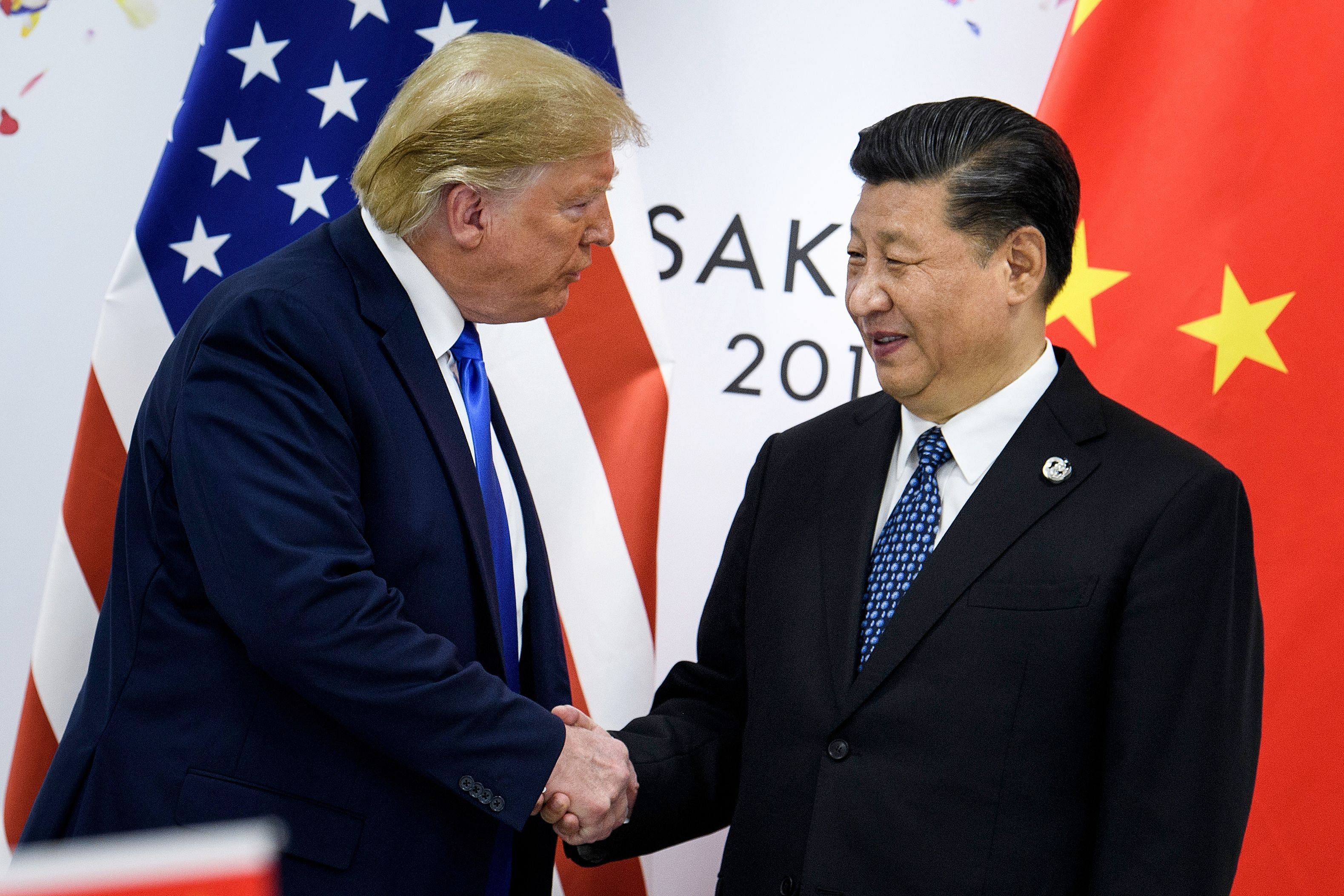 China's President Xi Jinping (R) shakes hands with US President Donald Trump before a bilateral meeting on the sidelines of the G20 Summit in Osaka. - Donald Trump pleaded with China's leader Xi Jinping for help to win re-election in 2020, the US president's former aide John Bolton writes in an explosive new book, according to excerpts published June 17. (Photo by AFP)