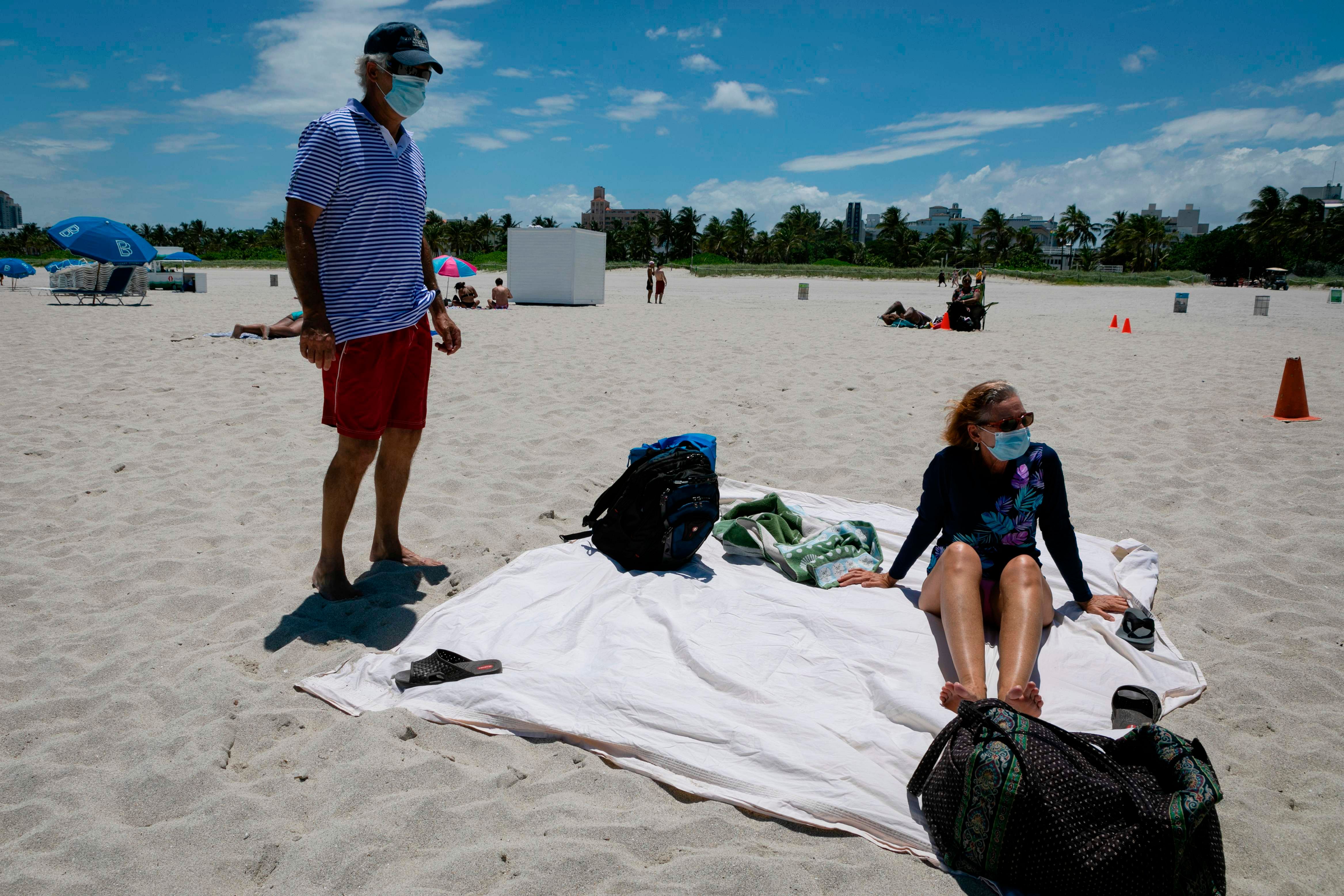 Diane, a nurse from Houston, Texas, sunbathes at the beach next to her husband, both wearing facemasks, in Miami Beach. Credits: AFP Photo