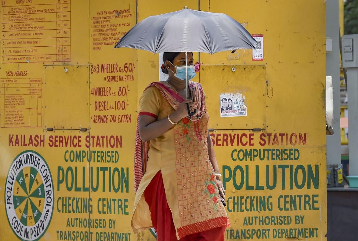 A woman walks under an umbrella to protect herself from the scorching heat, in New Delhi. PTI