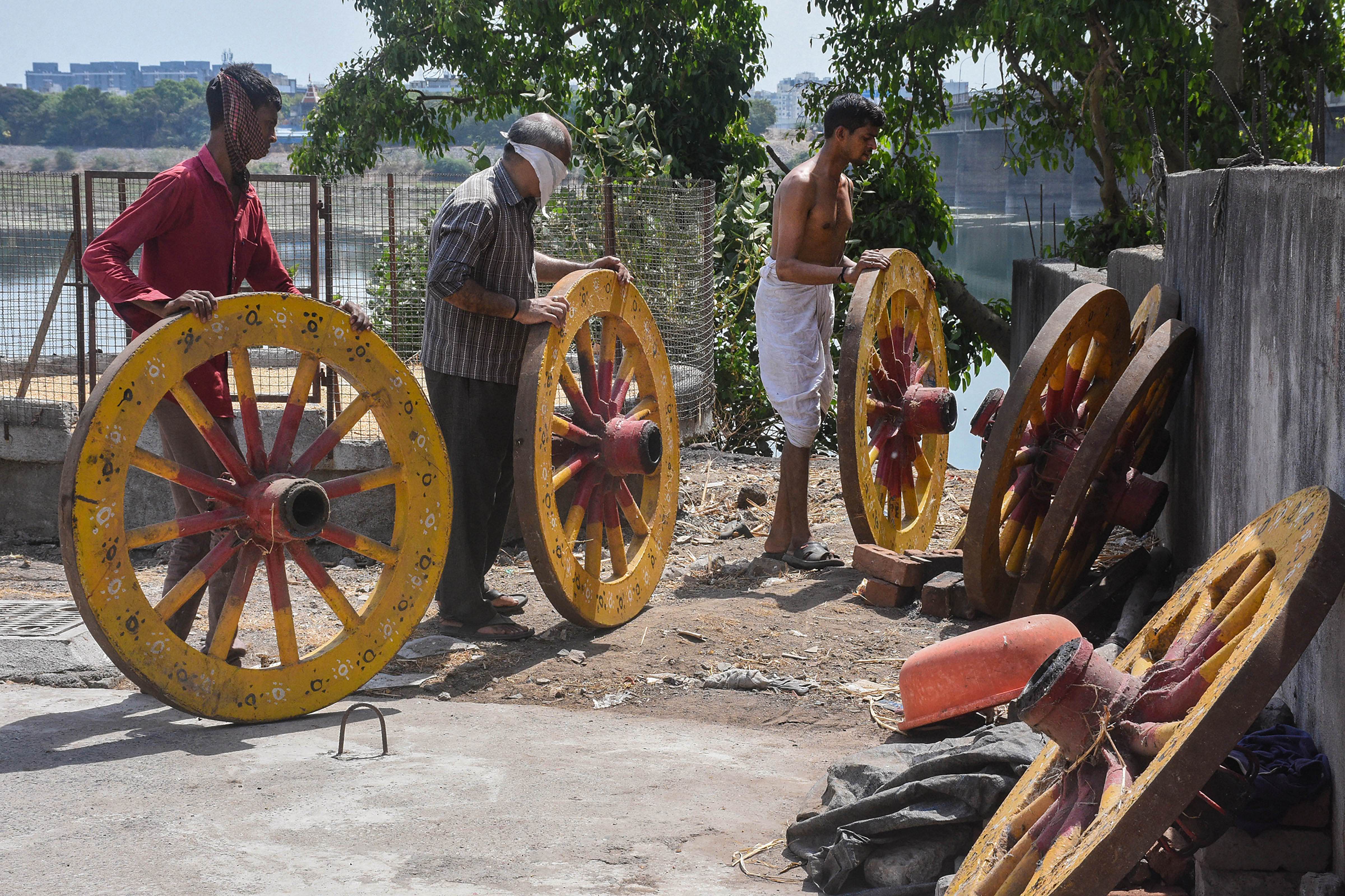Devotees hold wheels of the chariot during preparation work ahead of 'Rath Yatra' Festival at Jagannath temple, in Lanka Vijay Hanuman temple in Surat. Credits: PTI Photo