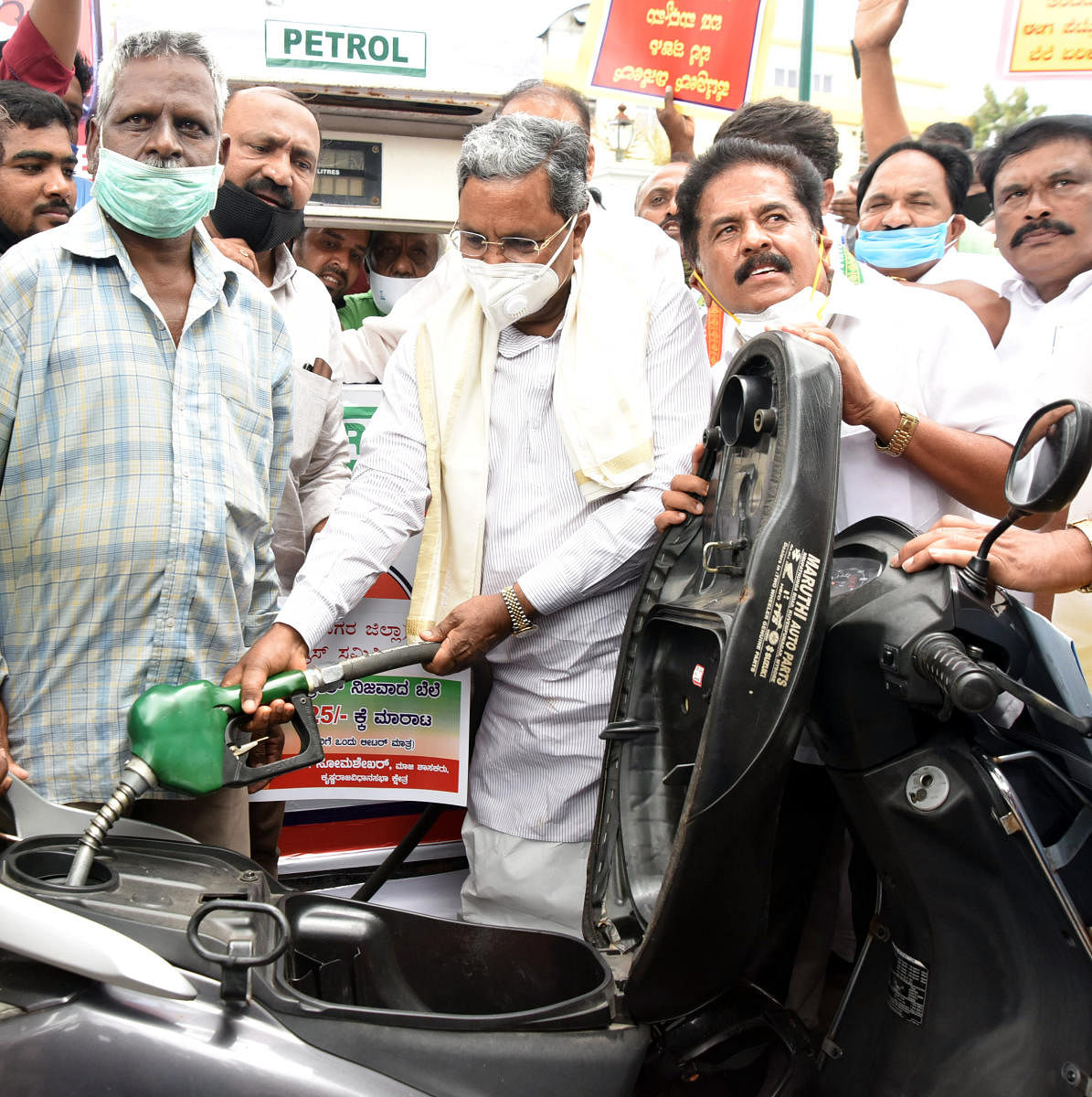Former chief minister Siddaramaiah fills petrol in a two-wheeler during a protest at Chikkammaniketana Marriage Hall in Mysuru on Friday. Ex-MLA M K Somashekar is seen. DH PHOTO