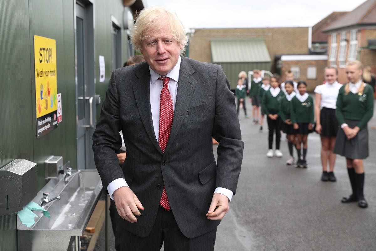 Britain's Prime Minister Boris Johnson gestures after washing his hands at a sink in the playground during a visit to Bovingdon Primary School in Bovingdon, Hemel Hempstead, Hertfordshire on June 19, 2020, following the announcement of a one billion pound plan to help pupils catch up with their education before September after spending months out of school during the novel coronavirus COVID-19 lockdown. Credit/AFP Photo