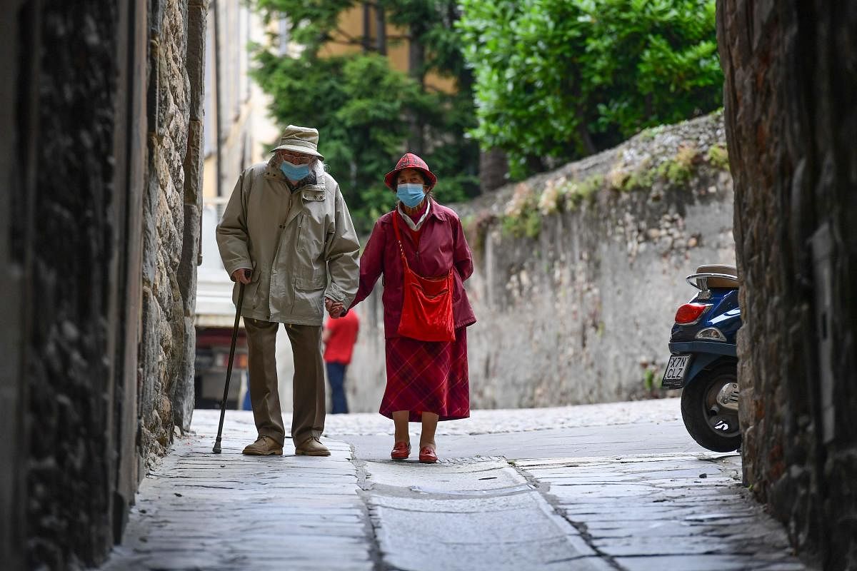  In this file photo taken on June 10, 2020 An elderly couple wearing face masks and holding hands walk in a street in the upper city of Bergamo on June 10, 2020, as Italy eases lockdown measures taken to curb the spread of the COVID-19 disease, caused by the novel coronavirus. Credit/AFP Photo