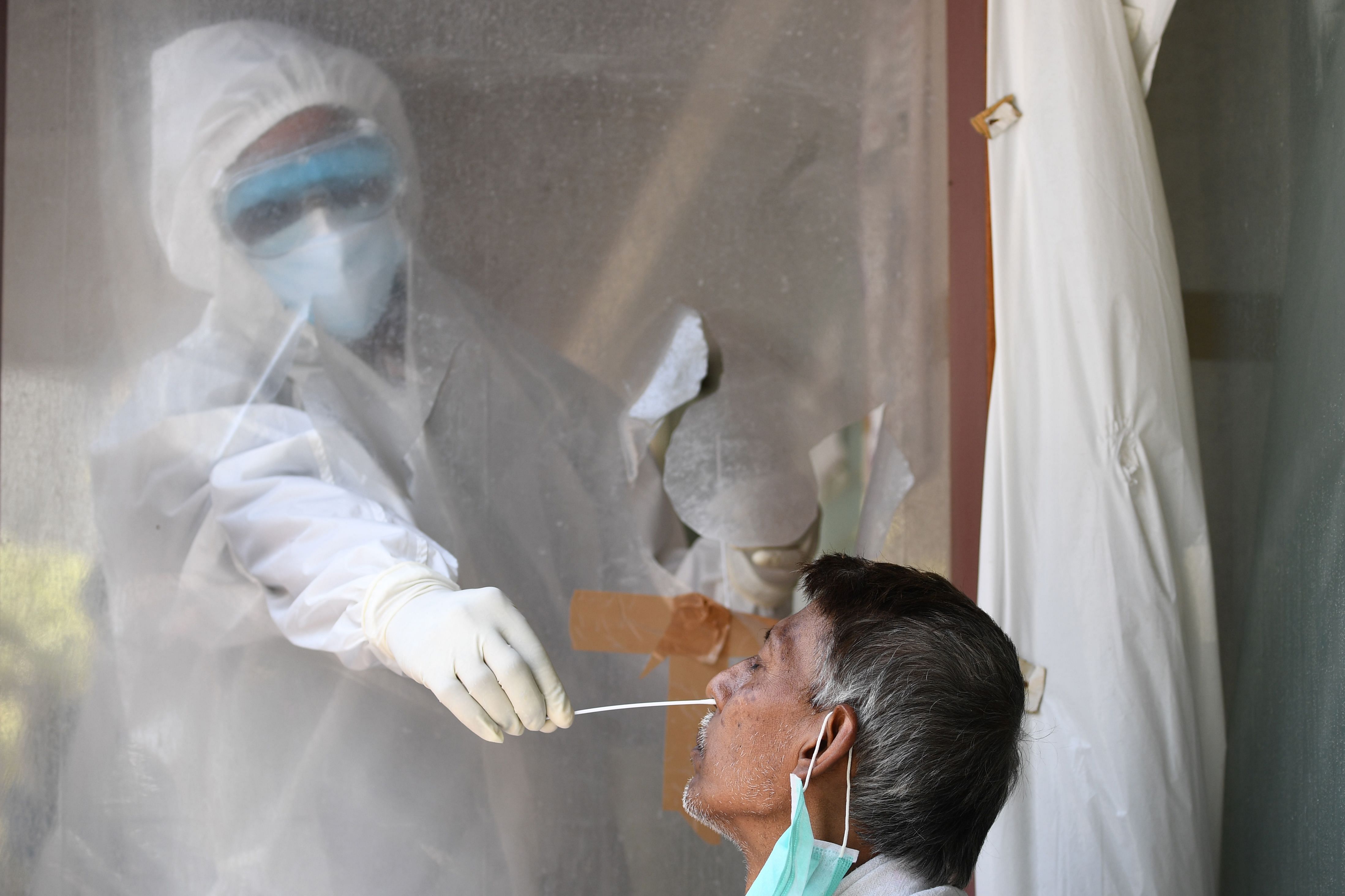 A health official collects a swab sample from a man to test for the COVID-19 coronavirus after authorities eased restrictions imposed as a preventive measure against the spread of the COVID-19 coronavirus, in New Delhi. Credit: AFP