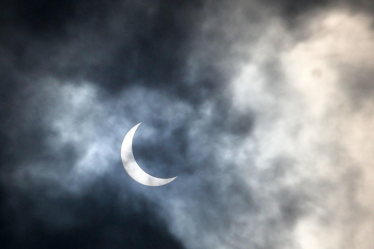 The moon moves in front of the sun during an annular solar eclipse as seen through clouds from Allahabad on June 21, 2020. Credit/AFP Photo