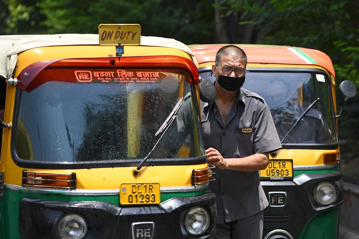 A driver pushes an auto rickshaw after disinfectant was sprayed on his vehicle along the roadside after the government eased a nationwide lockdown imposed as a preventive measure against the COVID-19 coronavirus, in New Delhi on June 11, 2020. Credit/AFP Photo