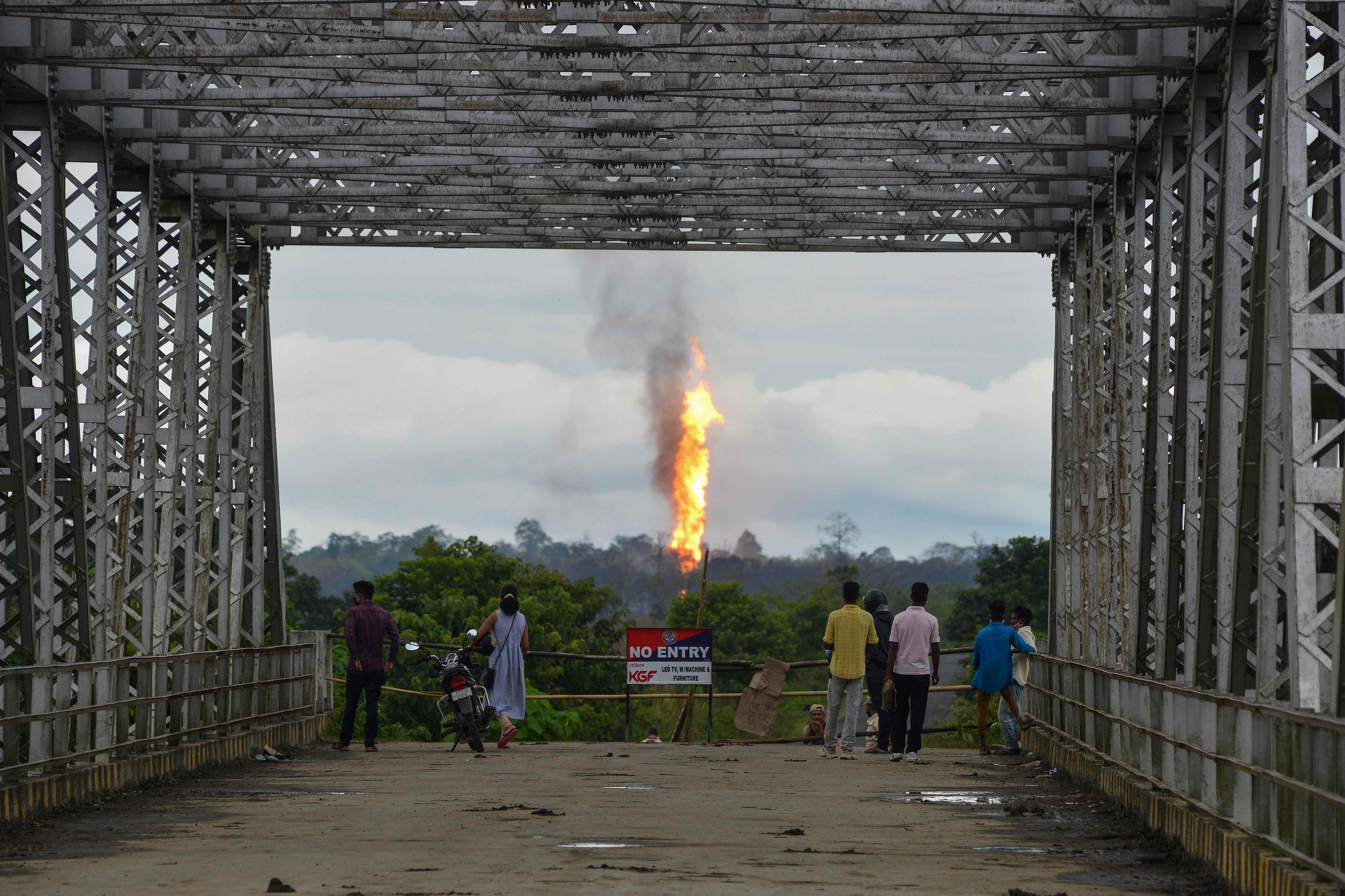  Two workers have been found dead near the site of a huge fire ignited by gas that has been spewing from an oil field in India for two weeks, officials said. A wall of flames and smoke continues to roar into the sky two days after the gas triggered an explosion at the well run by state-owned Oil India in the northeastern state of Assam. (Photo by AFP)