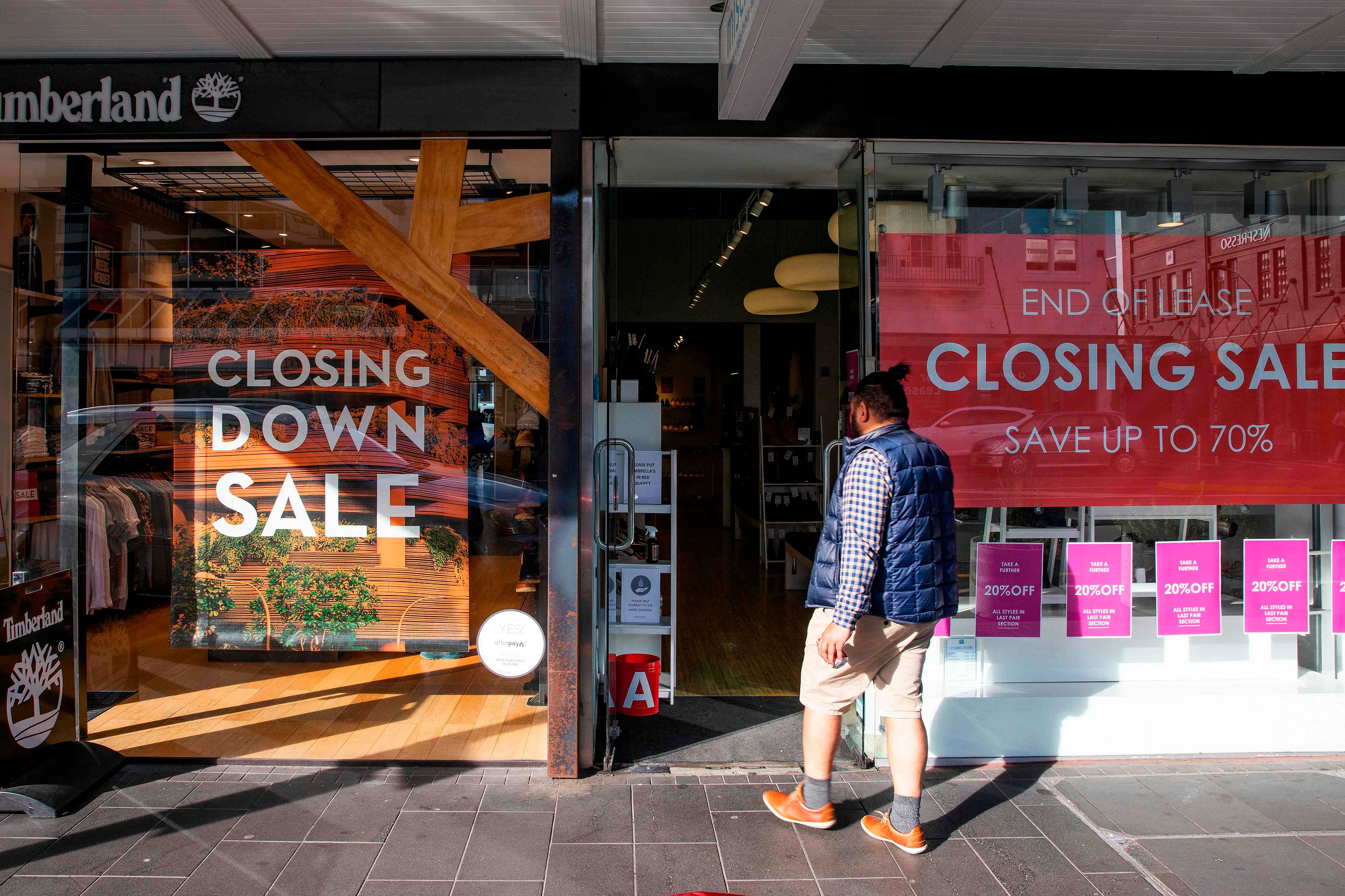A shopper makes his way into a store offering a closing down sale in Auckland. Credits: PTI Photo