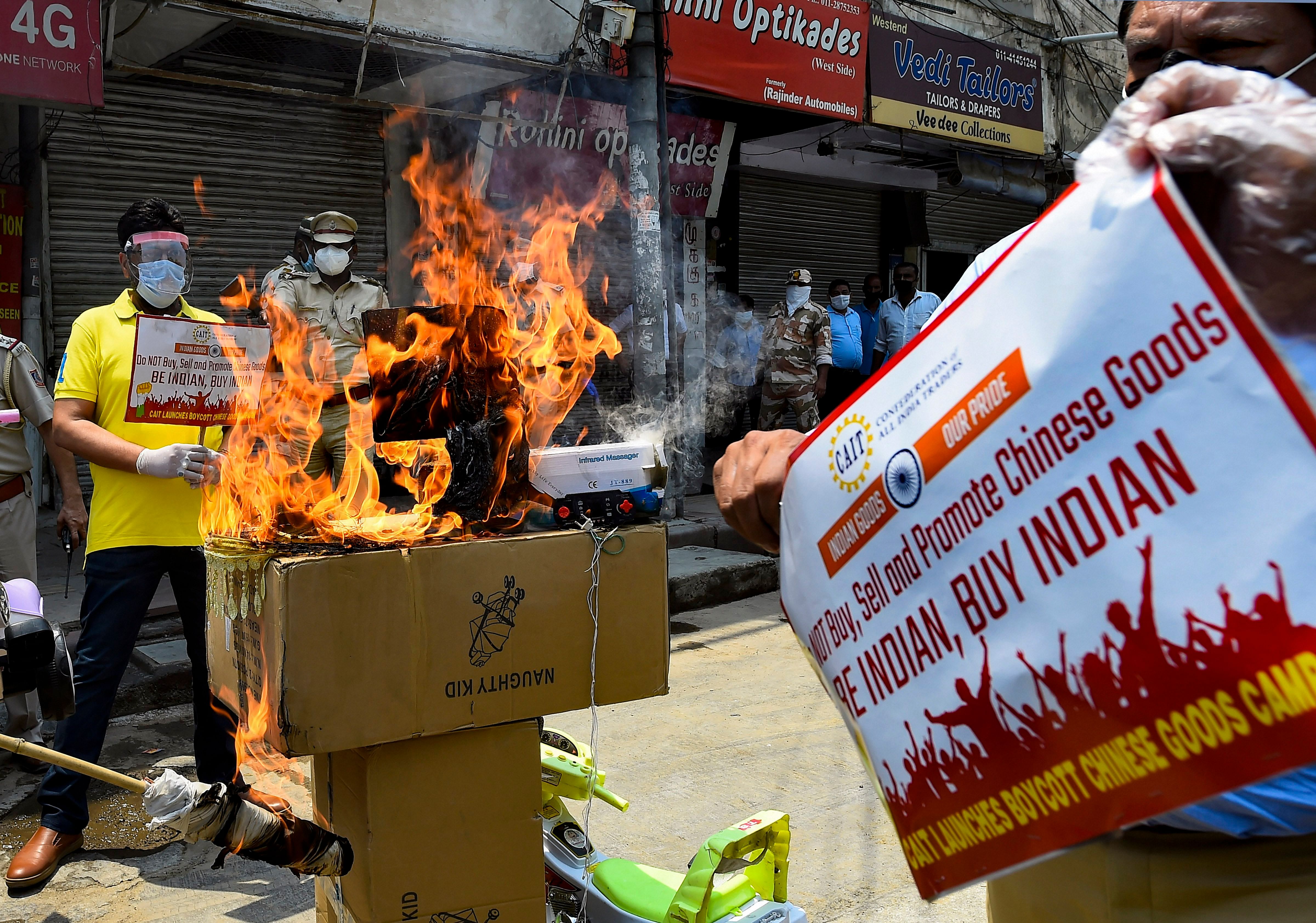 Activists of Confederation of All India Traders (CAIT) burn Chinese goods during a protest against the killing of 20 soldiers by Chinese troops in Ladakh last week, in New Delhi, Monday, June 22,2020. (PTI Photo)