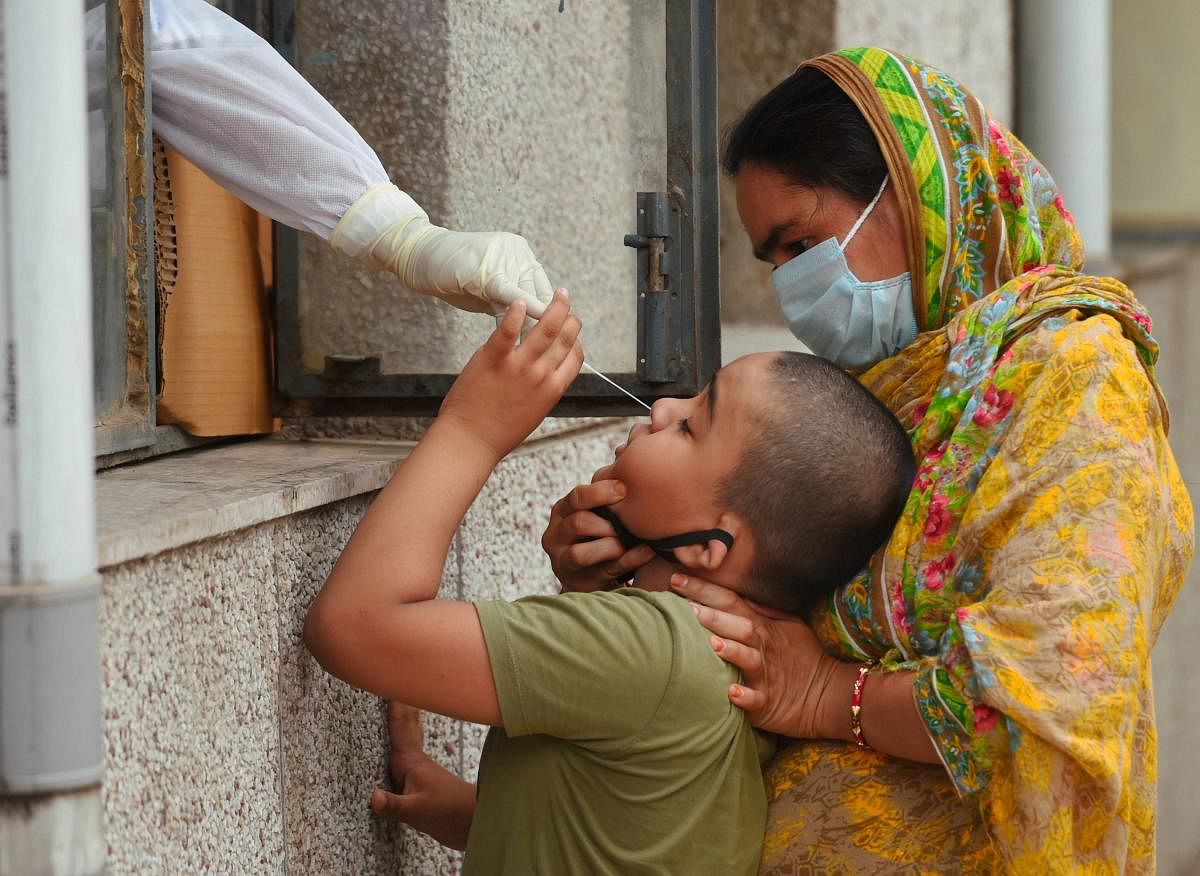 A medic takes a sample of a boy for COVID-19 test via Rapid Antigen at Govt school, in New Delhi. PTI