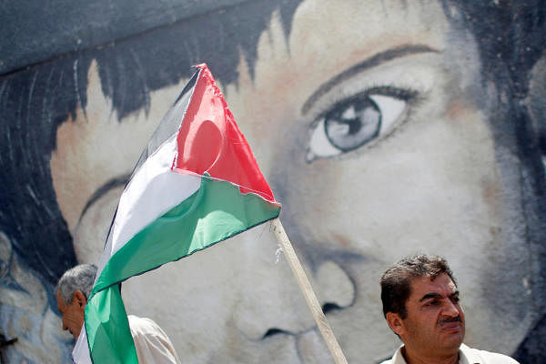 A demonstrator holding a Palestinian flag stands in front of a mural during a protest against Israel's plan to annex parts of the occupied West Bank, in Gaza City June 22, 2020. Credit: Reuters