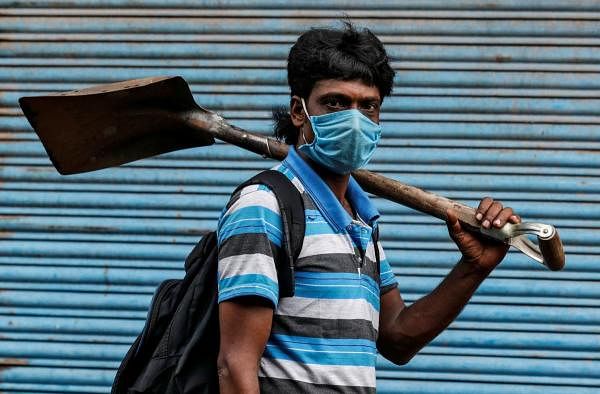 A migrant worker wearing a protective face mask goes to work after few restrictions were lifted, during an extended nationwide lockdown to slow the spread of the coronavirus. Credit: Reuters Photo