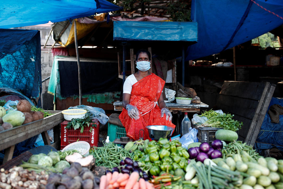 A woman wearing a protective face mask and gloves waits for customers at her vegetable shop outside a slum area, during an extended nationwide lockdown to slow the spreading of COVID-19, in New Delhi. Reuters