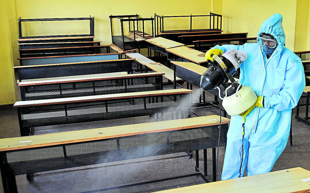 A health worker sprays disinfectant in a classroom in Karnataka Public School, Malleswaram, Bengaluru on Tuesday where SSLC examination will be held from June 25. DH Photo