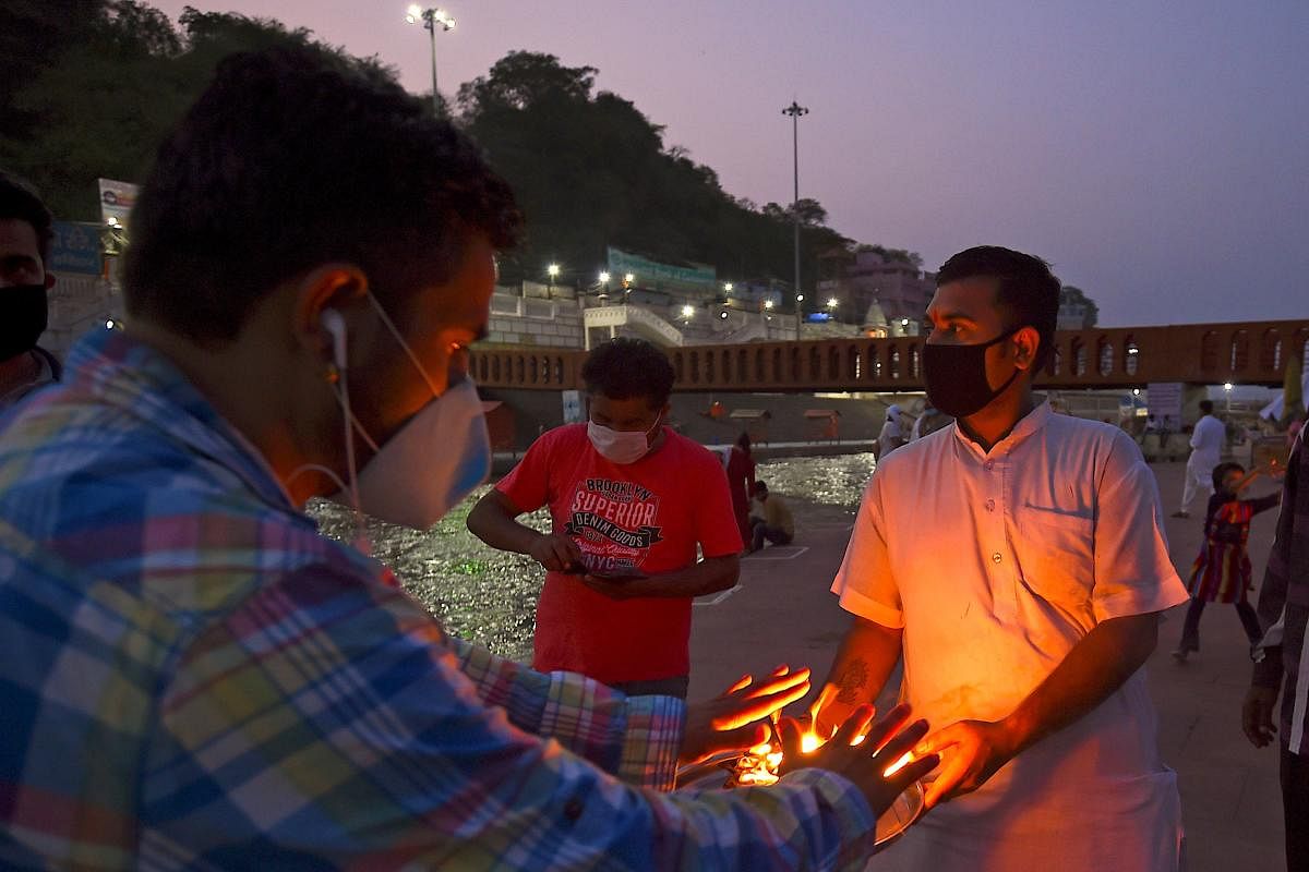 Hindu devotee takes blessings from holy fire after evening prayers at Har Ki Pauri ghat  (AFP Photo)