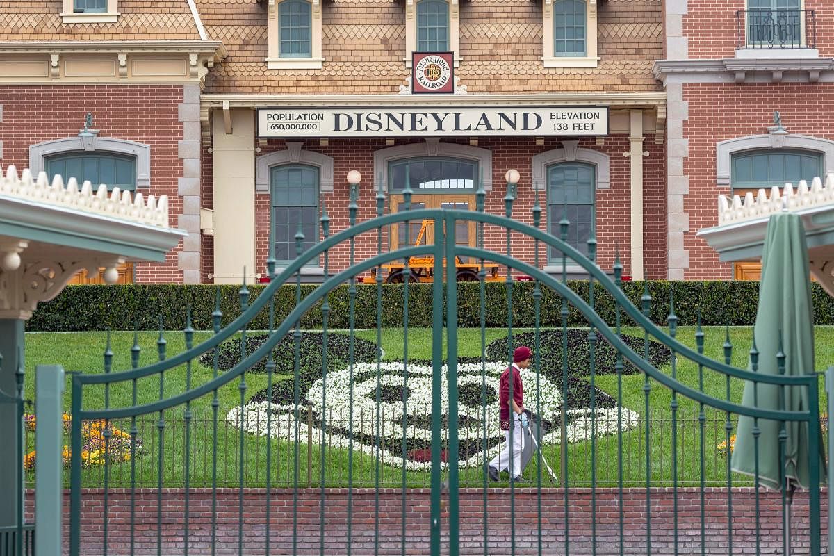 In this file photo an employee cleans the grounds behind the closed gates of Disneyland Park on the first day of the closure of Disneyland and Disney California Adventure theme parks as fear of the spread of coronavirus continue, in Anaheim, California, on March 14, 2020. Credit/AFP Photo