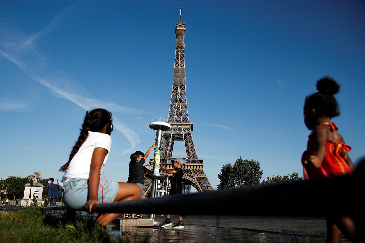 Children cool themselves off in a water fountain near the Eiffel Tower during a warm and sunny day in Paris as a heatwave hits France, June 24, 2020. Credit/Reuters Photo