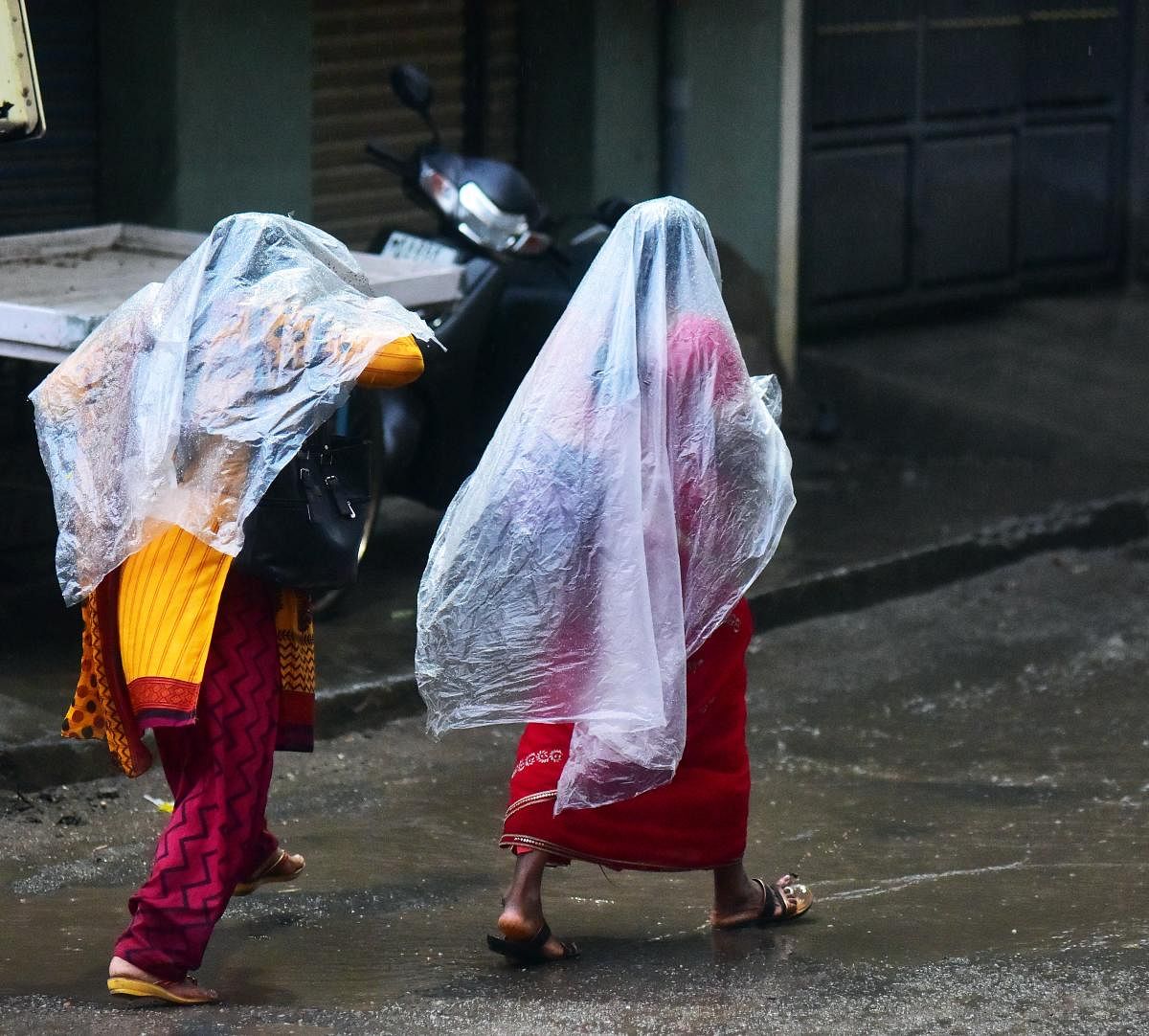 Two women run for cover in Srinagar following the evening showers on Wednesday. DH PHOTO/ANUP RAGH T