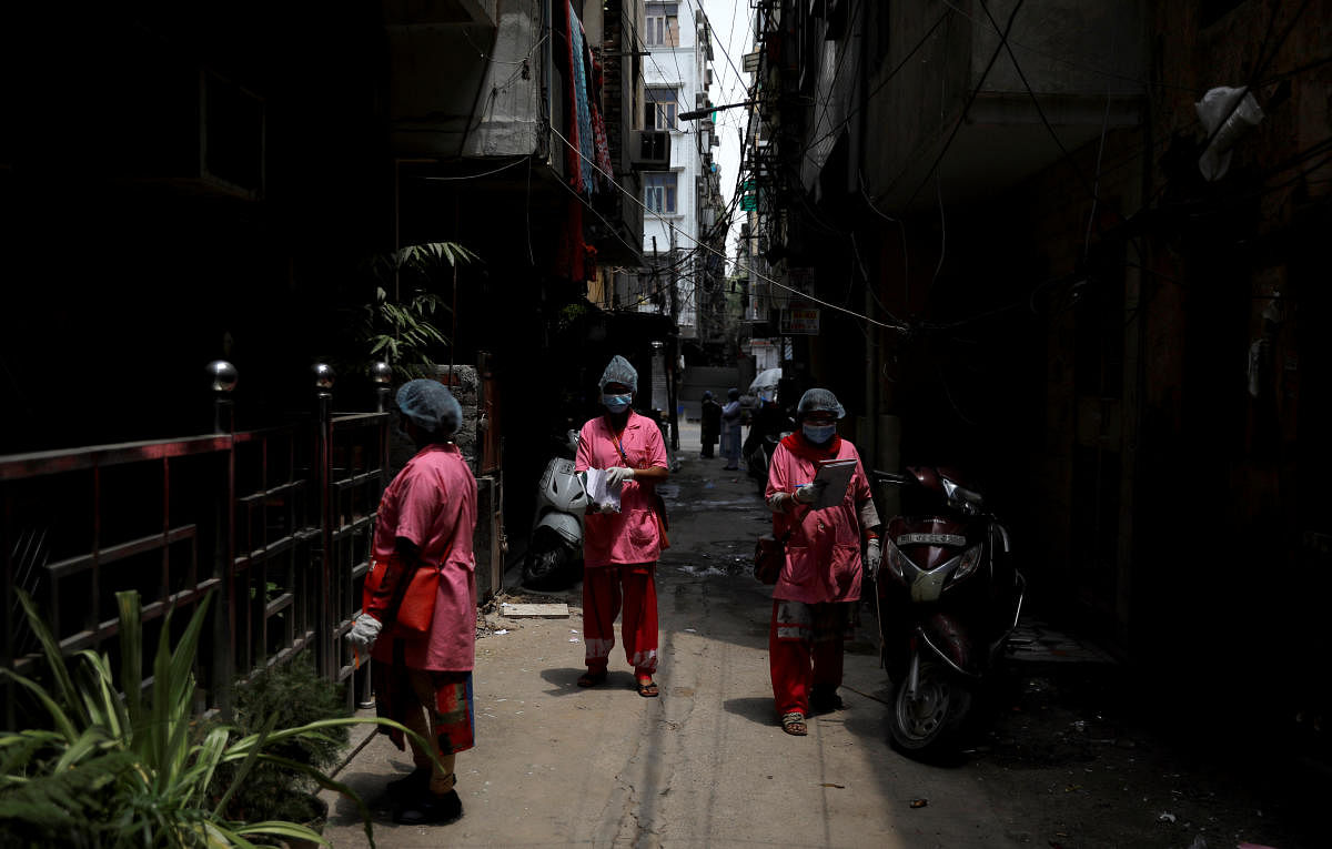 ASHA workers, community health workers instituted by the government of India's Ministry of Health and Family Welfare, are seen in an alley as they conduct a door-to-door survey for Covid-19 in New Delhi. Reuters