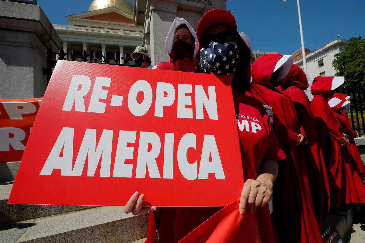 A woman holds a sign reading "Re-Open America" at a demonstration to demand lifting of restrictions imposed by state and local officials to fight the spread of the coronavirus disease (COVID-19) in Boston, Massachusetts, U.S., May 30, 2020. Credit/Reuters Photo