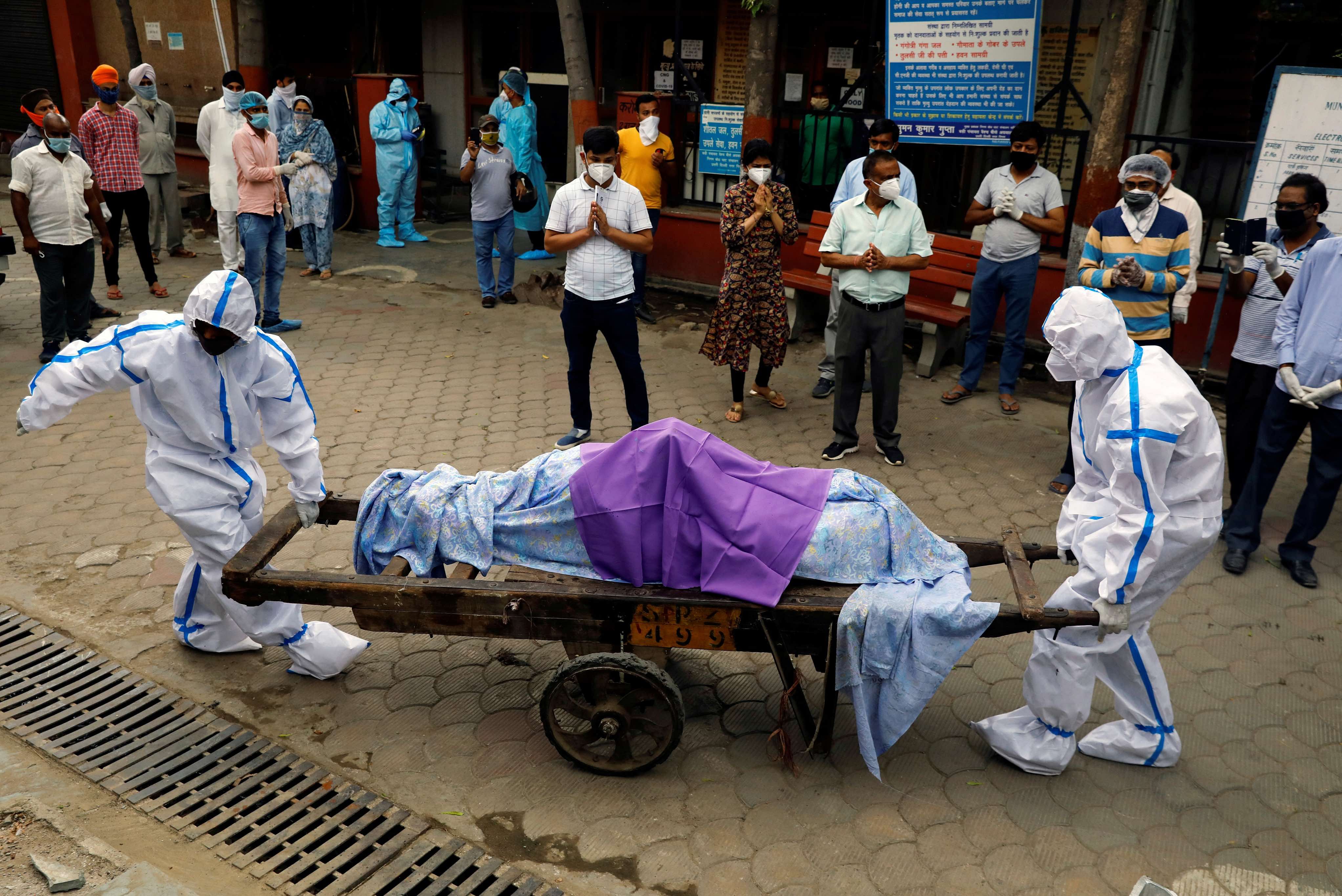 Health workers wearing Personal Protective Equipment (PPE) carry the body of a person who who died due to the coronavirus disease (COVID-19), at a crematorium in New Delhi. Credit: Reuters