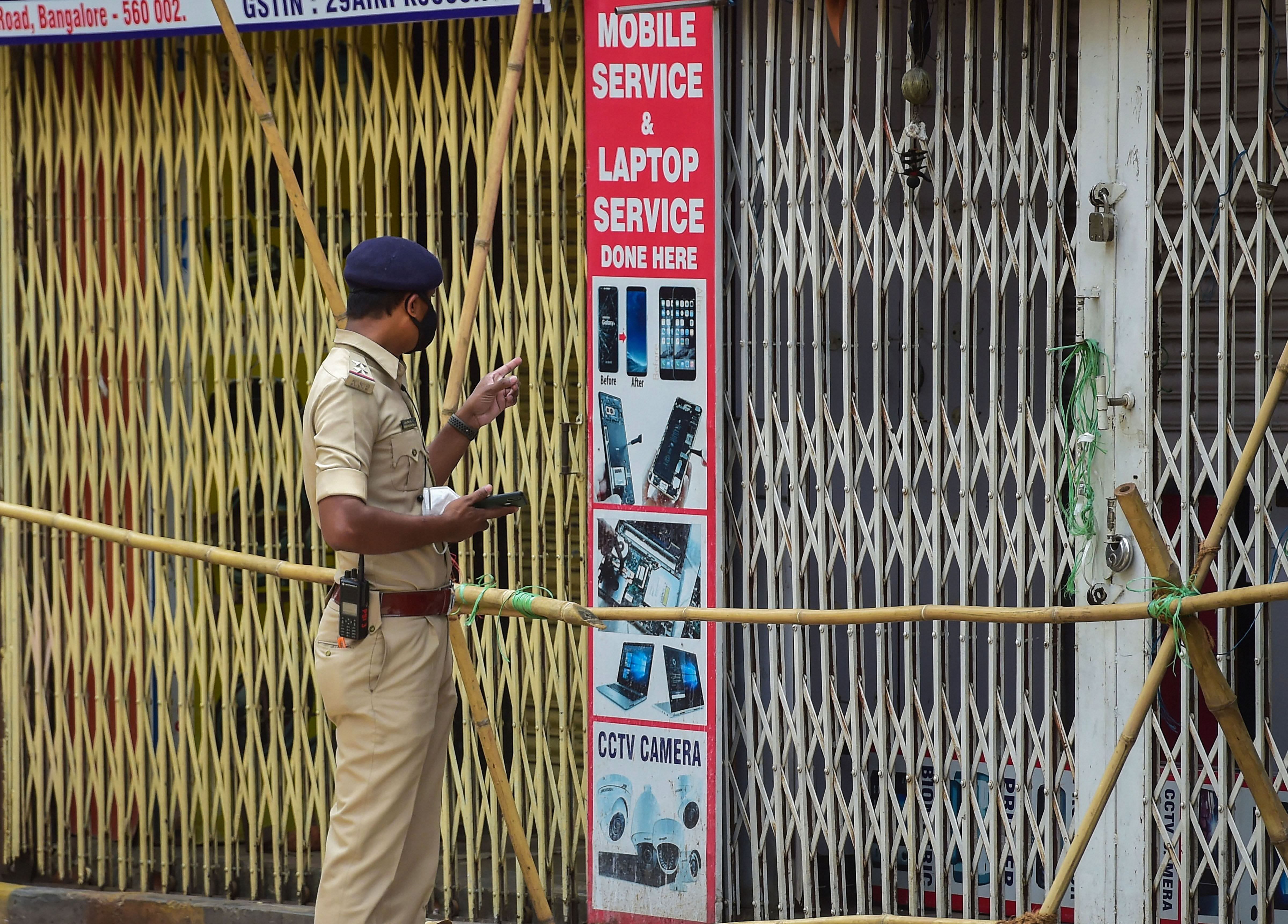  A policeman ensures closure of shops at Sadar Patrappa road locality as Karnataka government announced the area under lockdown after detection of several clusters of coronavirus infections, in Bengaluru. Credits: PTI Photo
