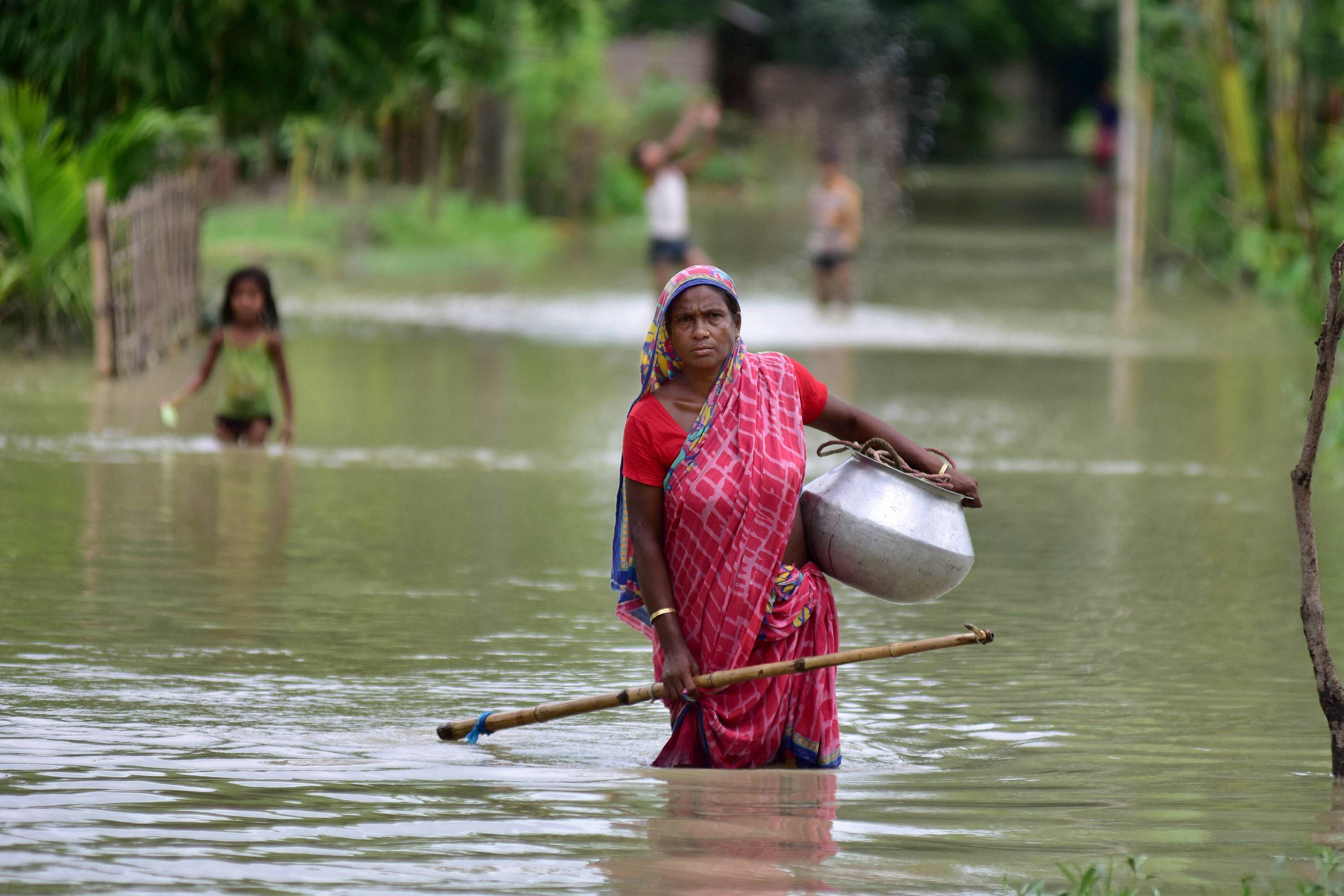 A woman wades through a flooded area at a village, in Nagaon district. Credits: PTI Photo