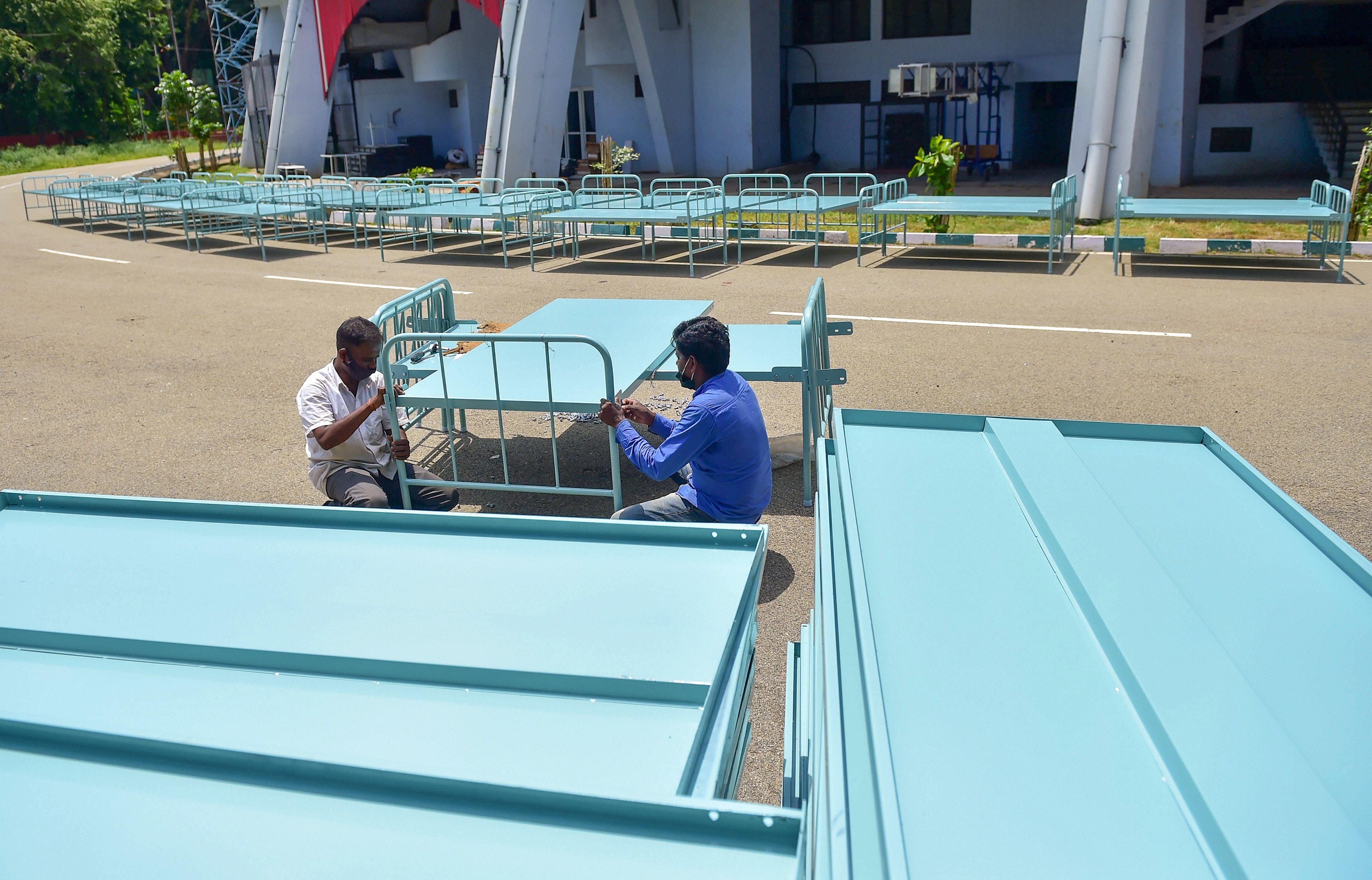 Workers fix beds at Kanteerava stadium for COVID Care Centre, in Bengaluru. Credits: PTI Photo