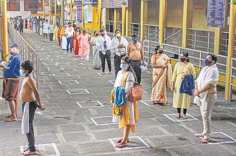 Devotees maintain social distance while standing in a queue to pay obeisance at Kukke Subramanya Temple, after religious places reopened with certain restrictions, during the fifth phase of ongoing COVID-19. Credits: PTI Photo