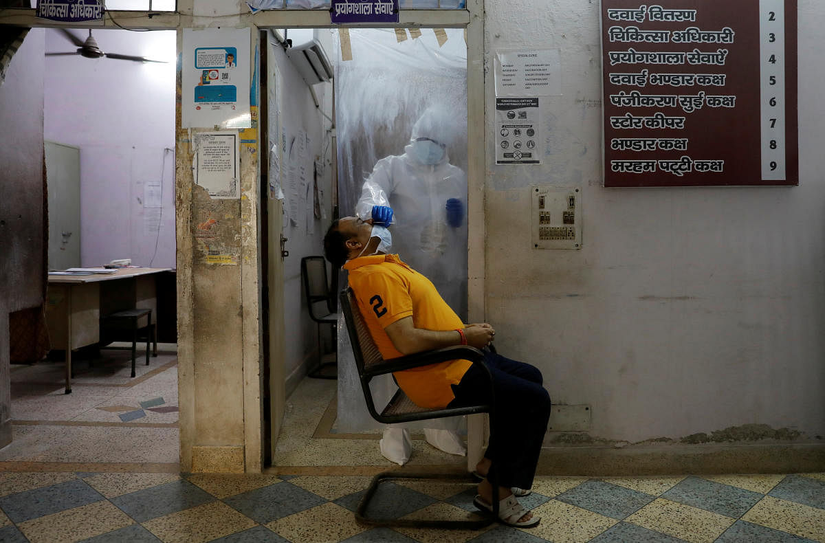 A health worker in personal protective equipment (PPE) collects a sample using a swab from a person at a local health centre to conduct tests for the coronavirus disease (COVID-19), amid the spread of the disease, in New Delhi, India June 27, 2020. REUTER