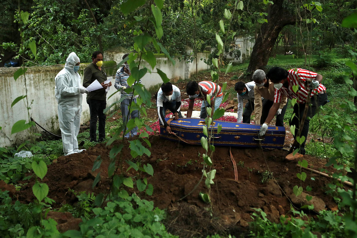 A priest wearing personal protective equipment (PPE) prays over the coffin of a person who died from the coronavirus disease (COVID-19) during a funeral at a cemetery in Mumbai, India June 27, 2020. Credit/Reuters Photo