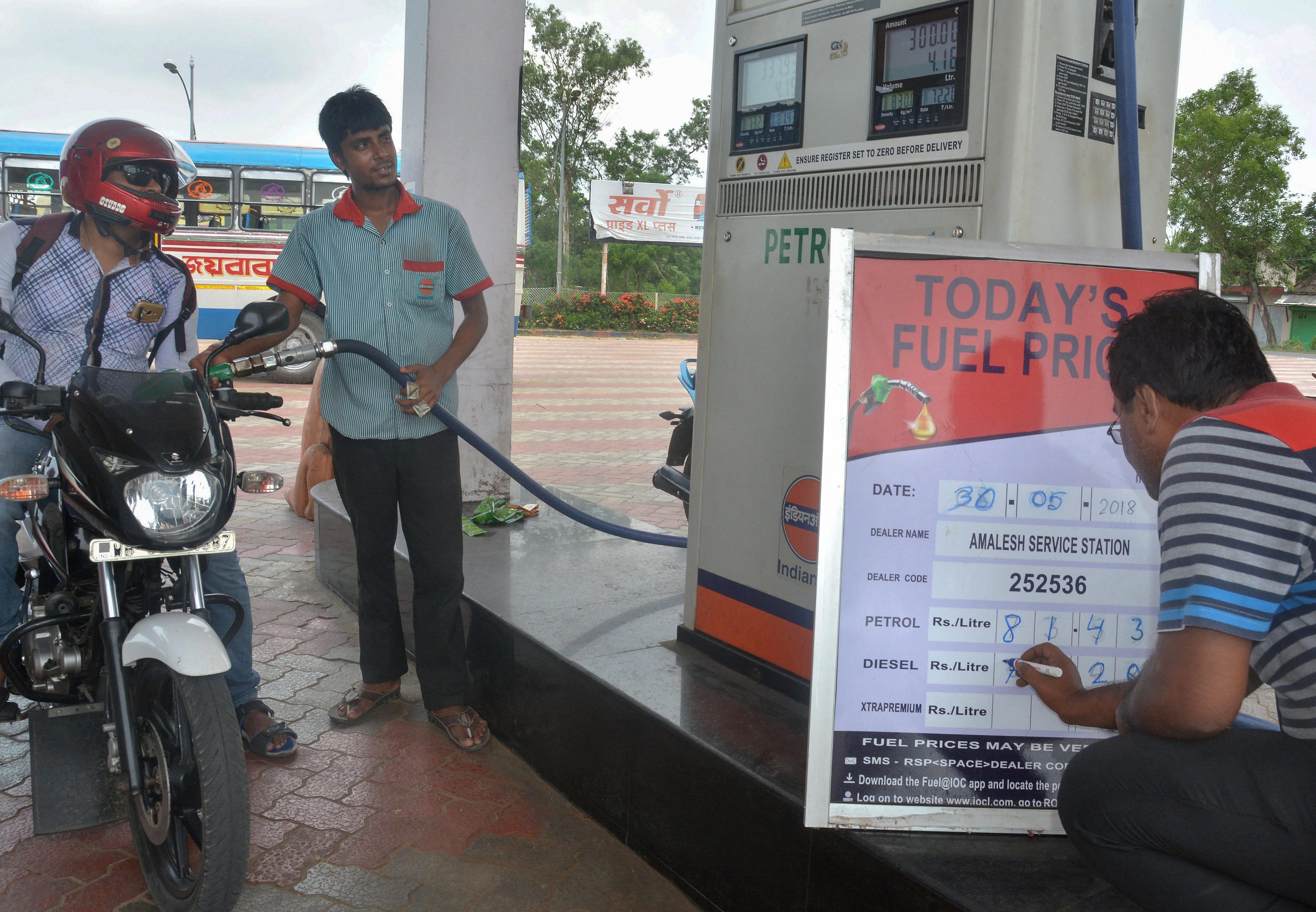 An employee updates fuel prices display board at a petrol pump, in Howrah. Credits: PTI Photo