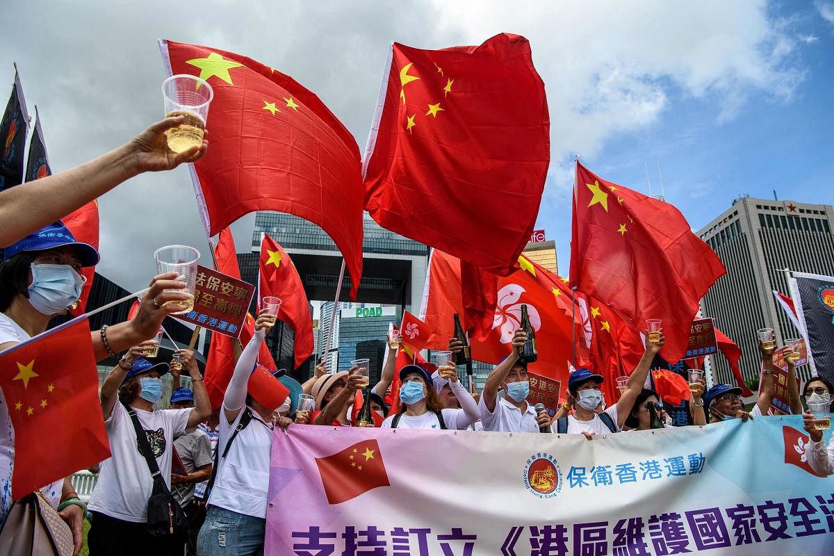 Pro-China supporters display Chinese and Hong Kong flags as they raise a toast with champagne during a rally near the government headquarters in Hong Kong. Credit: AFP